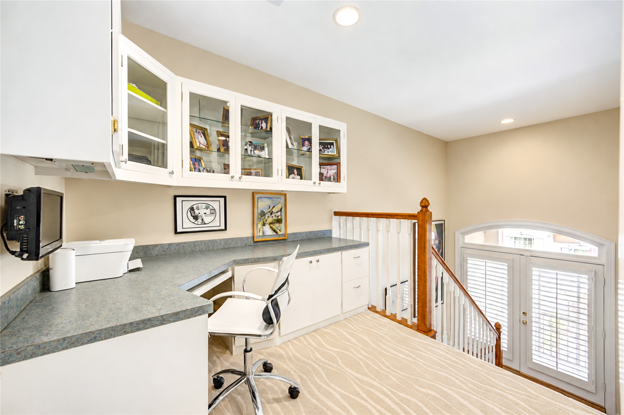 A beautifully designed third-floor office features a custom built-in desk, generous workspace and elegant glass-front cabinetry.