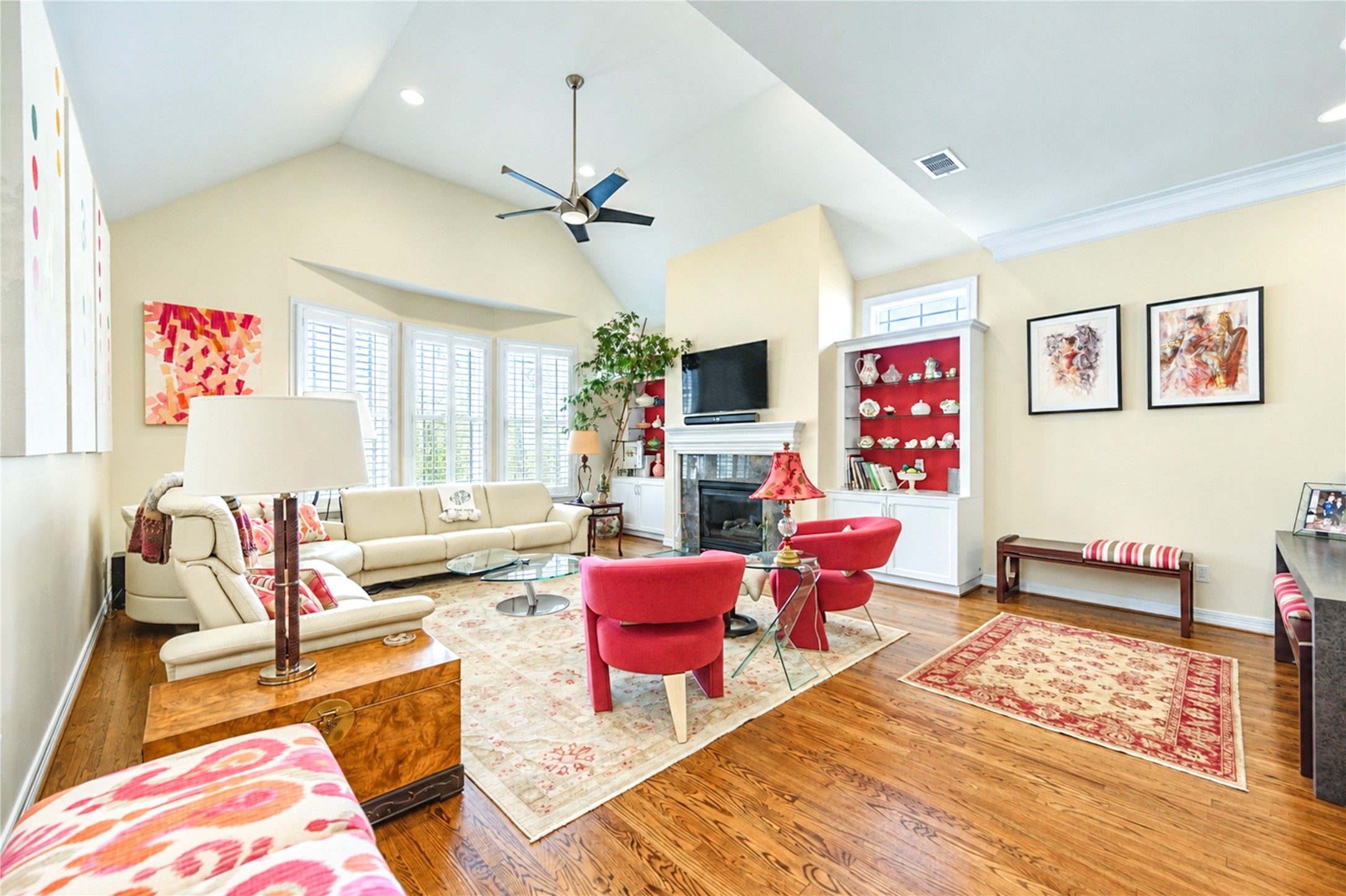 The vaulted second-floor living room pairs hardwood floors with a gas-log fireplace, custom built-in display cabinetry and a bank of shuttered windows. The vaulted second-floor living room pairs hardwood floors with a gas-log fireplace, custom built-in display cabinetry and a bank of shuttered windows.