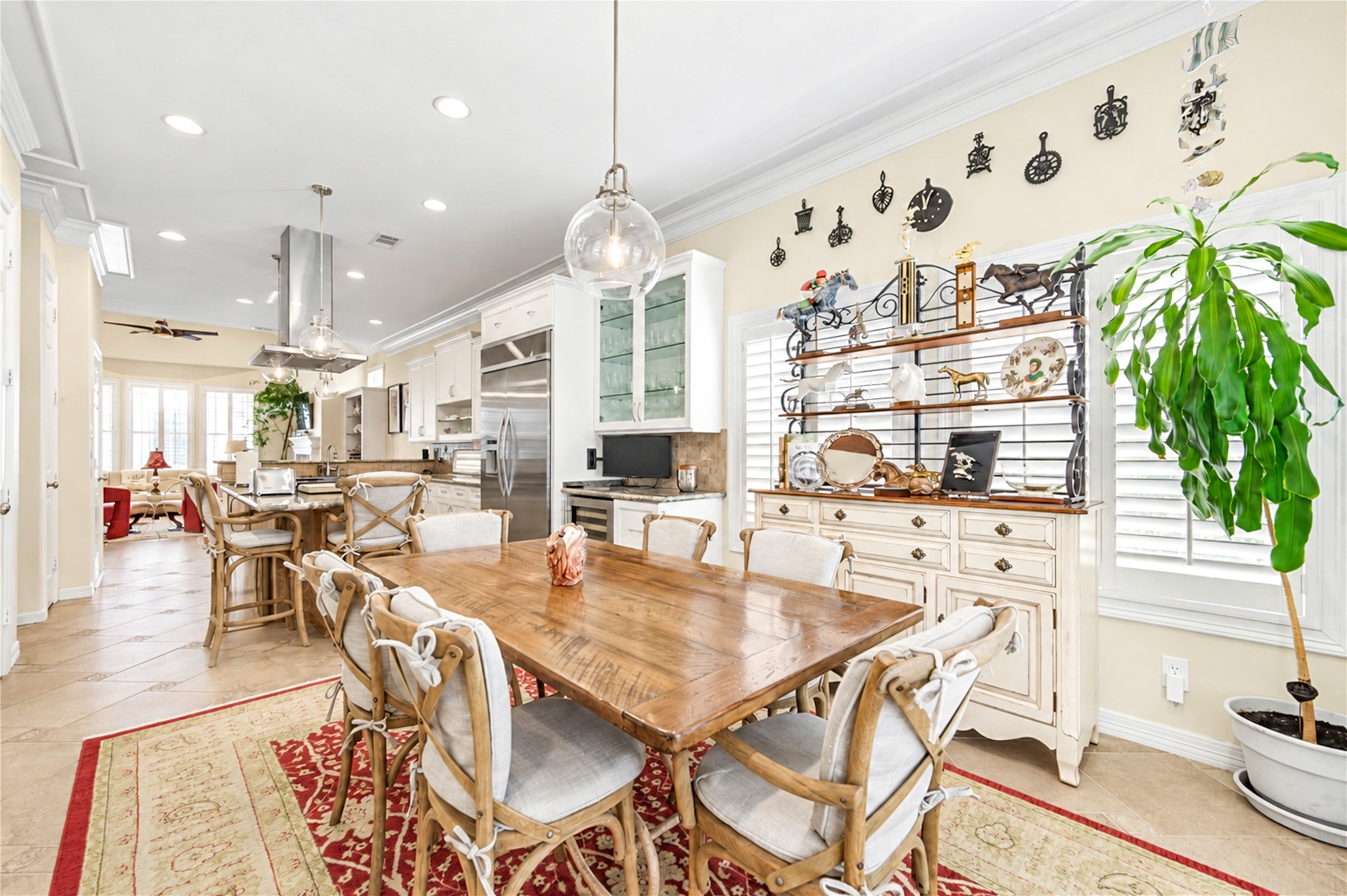 The kitchen opens to a sunlit breakfast area with tile flooring, shuttered windows and crown molding.
