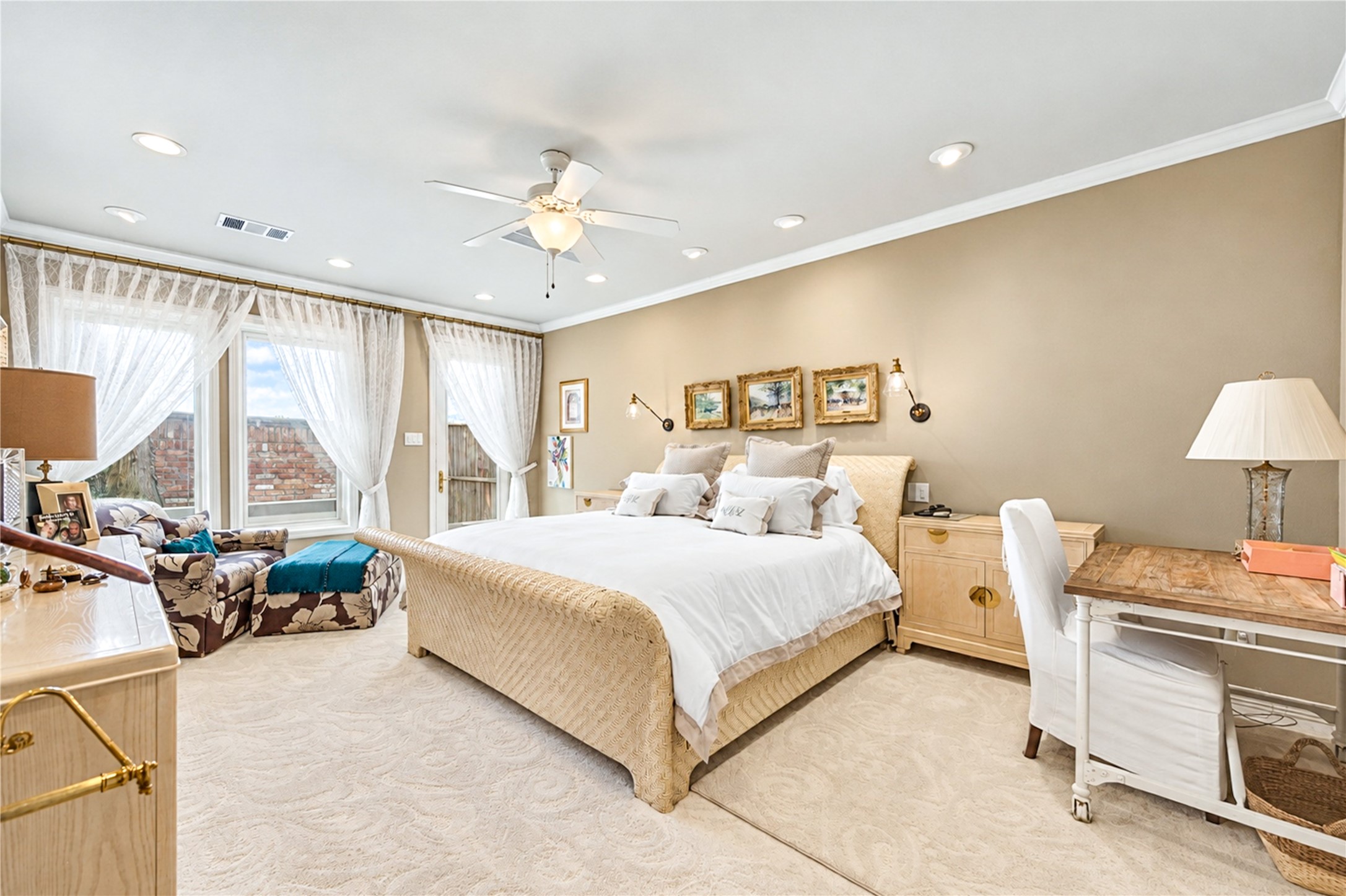 The first-floor primary bedroom is a spacious retreat with recessed lighting, crown molding, a ceiling fan and windows that fill the room with natural light.