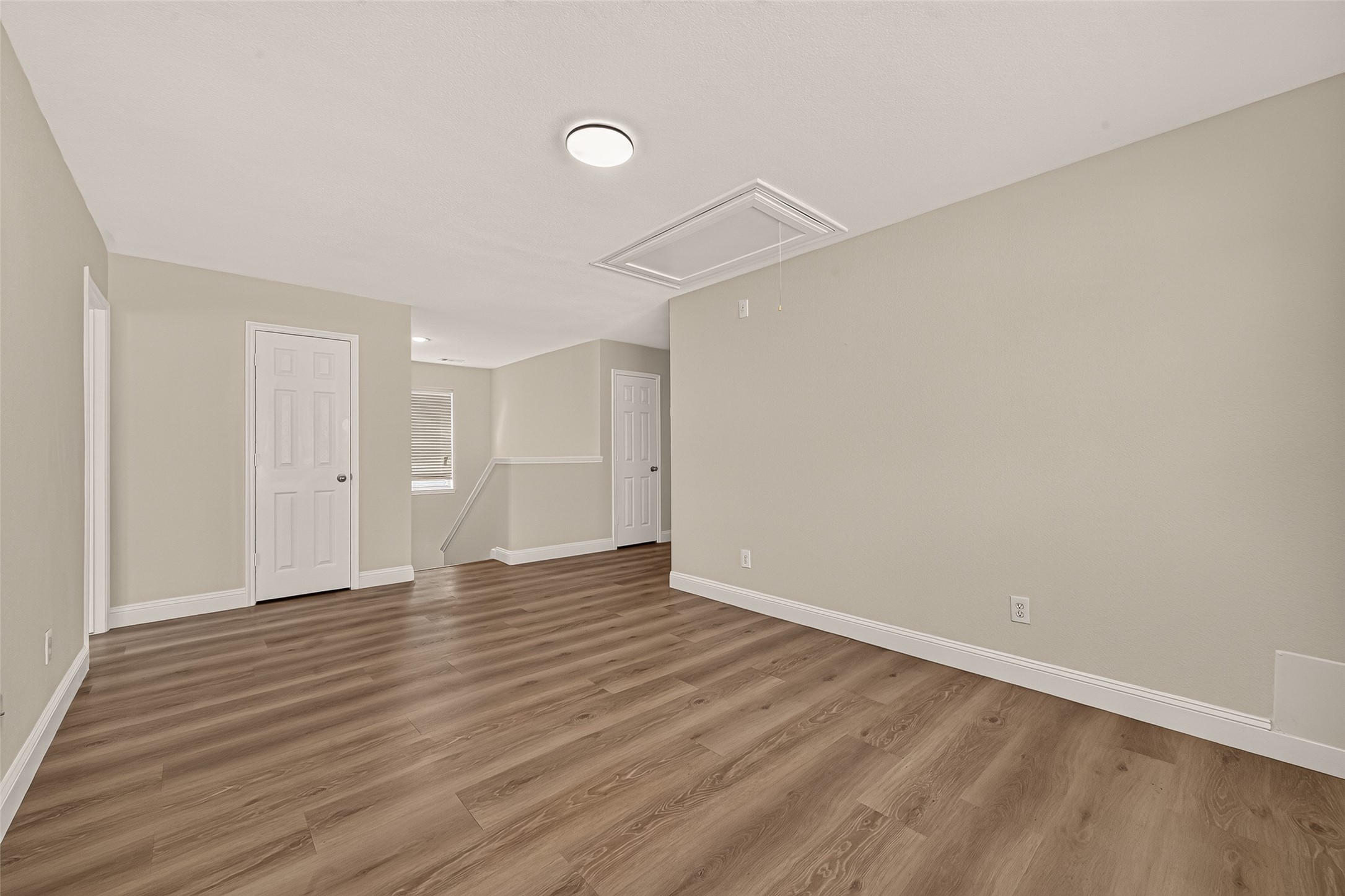 The upstairs landing opens into a spacious game room, where the warm wood-look flooring continues the home's consistent theme. The open footprint lends itself to recreation, hobbies, or a secondary lounge away from the main living areas.