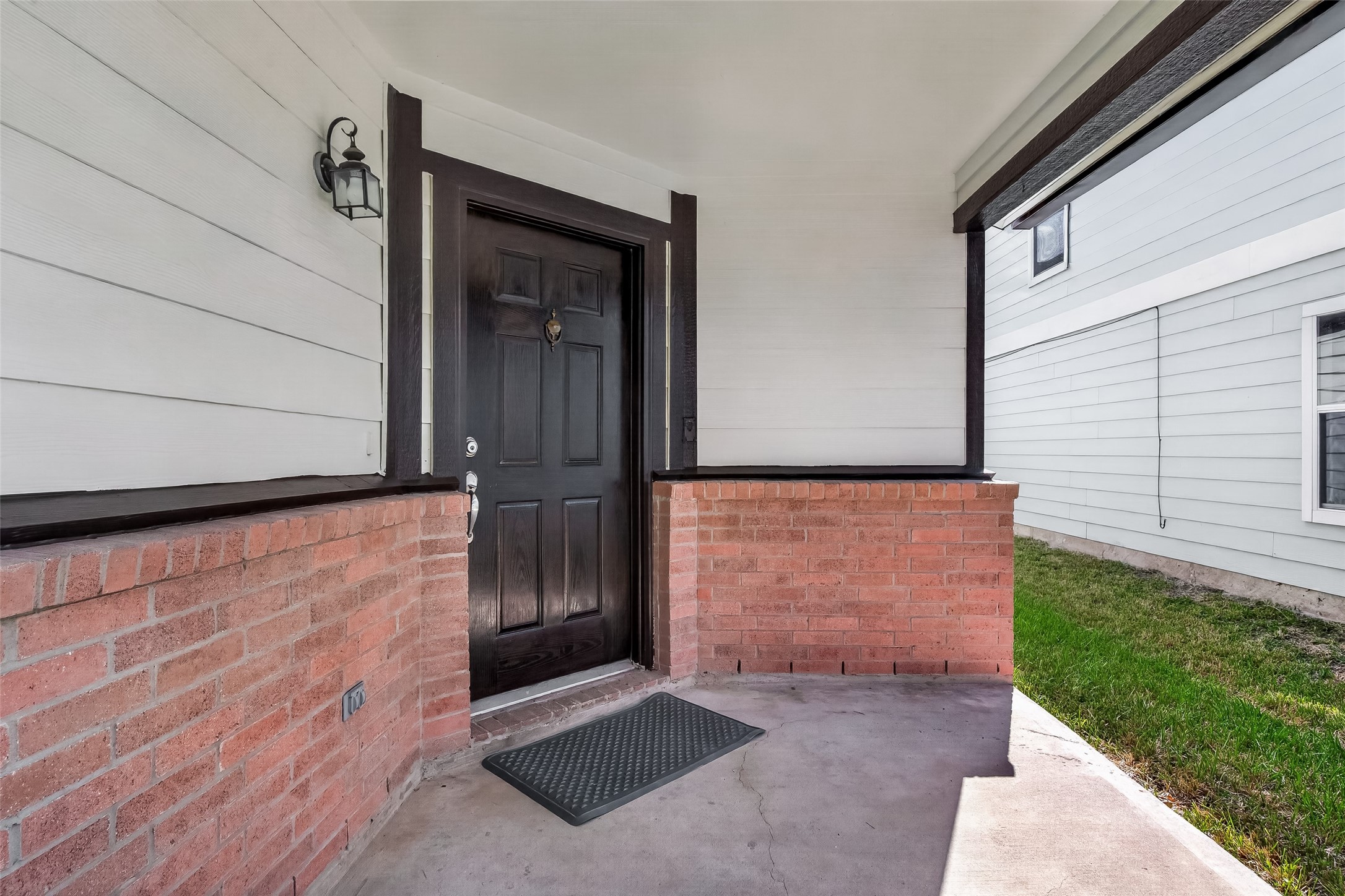 A closer look at the covered front entrance reveals a clean combination of brick and siding, giving the facade depth and a polished, well-kept appearance.