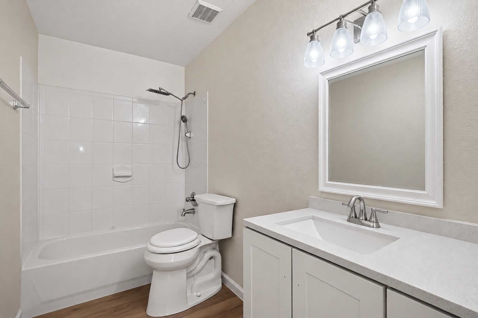 A well-appointed vanity sits alongside a tub-and-shower combination wrapped in clean tilework. The straightforward layout and neutral palette create a fresh, versatile bathroom suited to daily use.