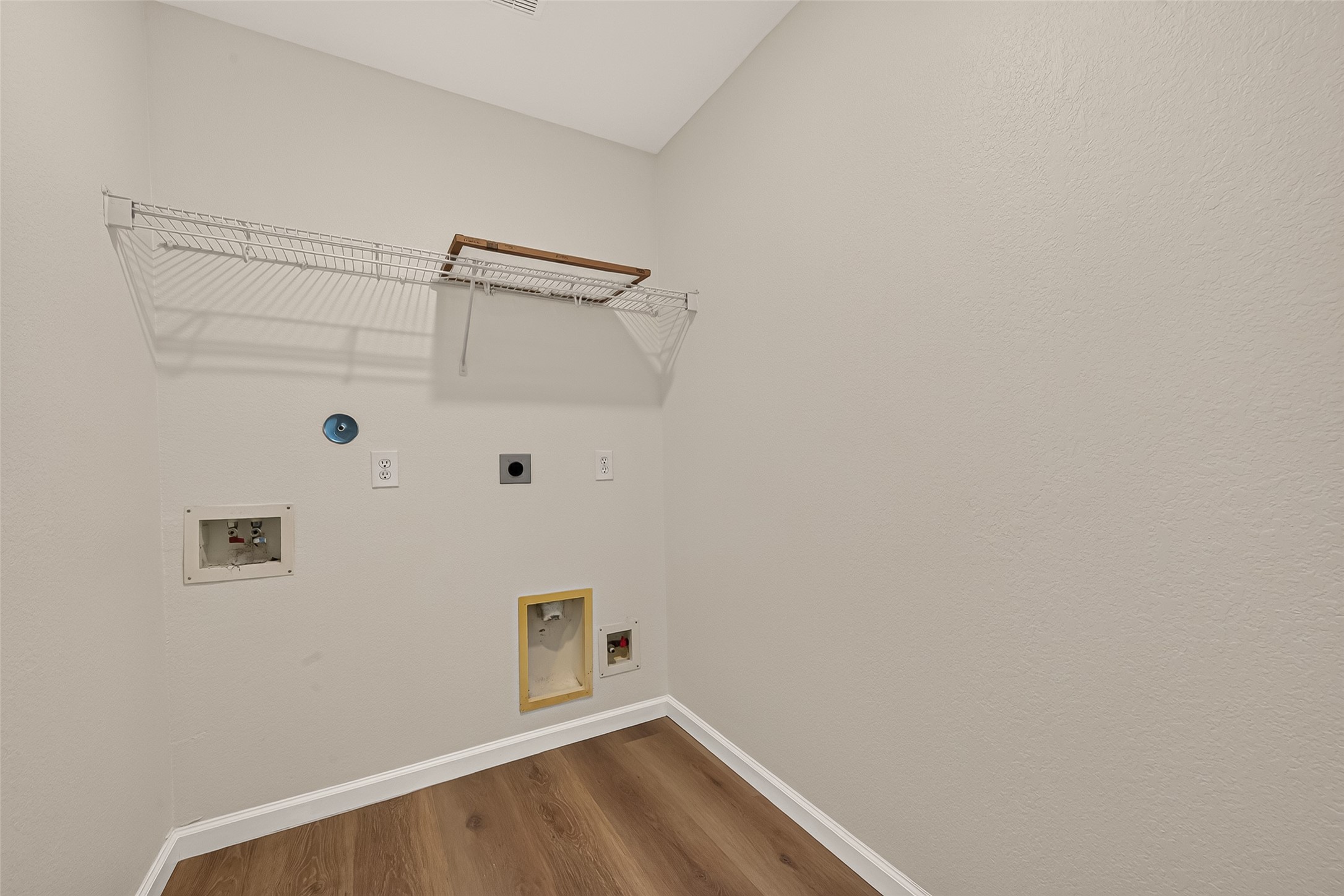 A built-in rack above the washer and dryer area makes use of vertical space, providing a handy spot for laundry essentials while keeping the home's chore routine organized.