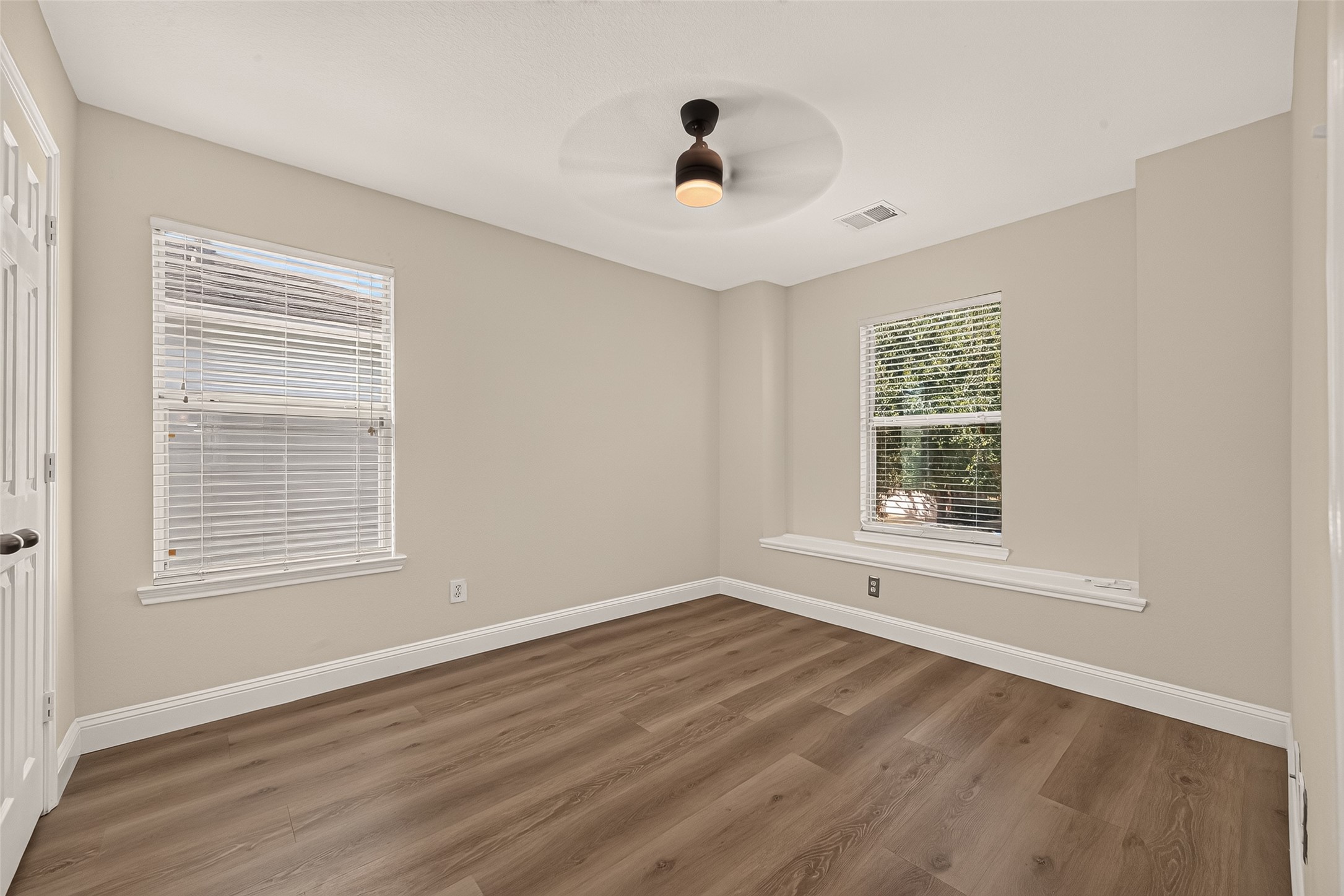 Soft neutral tones and a ceiling fan establish a relaxed setting, while the charming window seat adds a distinctive detail and a cozy spot to read, pause, or enjoy the natural light.