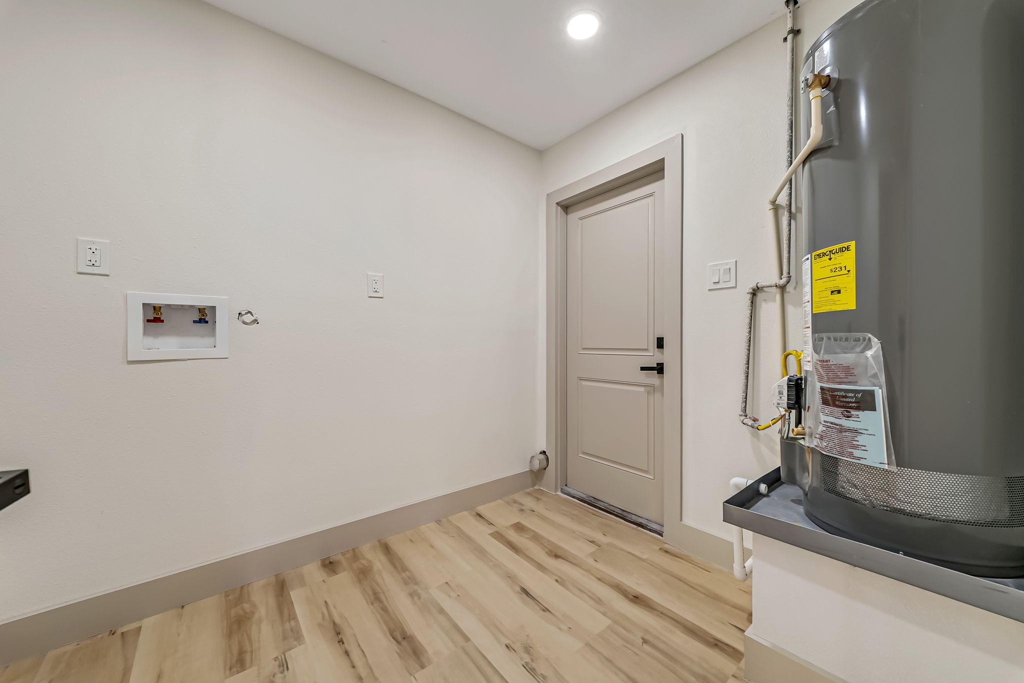 Spacious laundry room with modern hookups, a water heater, and sleek flooring, providing functionality and style.