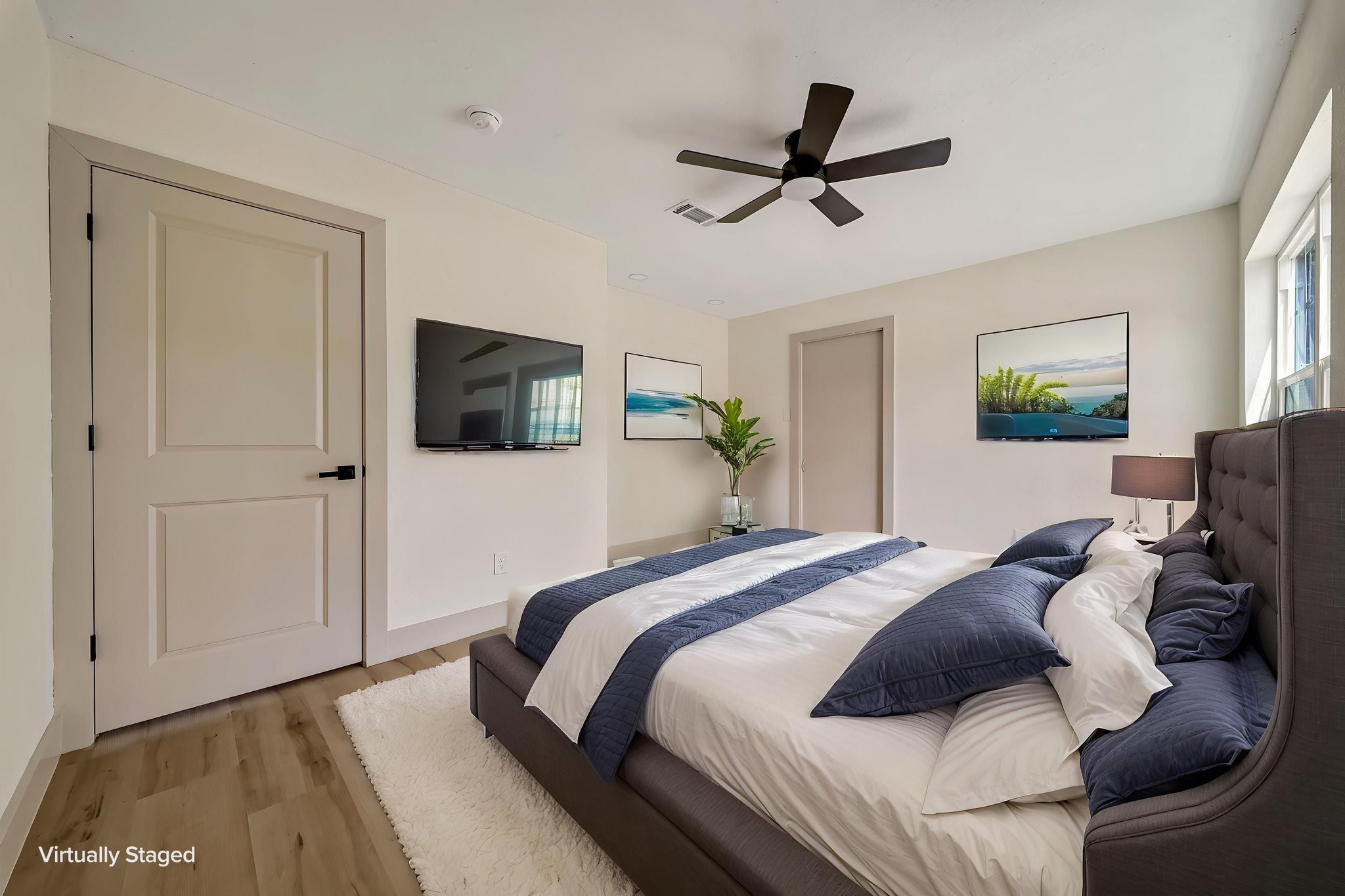 (Photoshopped) Experience modern elegance in this virtually staged bedroom, featuring a sleek ceiling fan, stylish furnishings, and abundant natural light that creates a serene retreat.