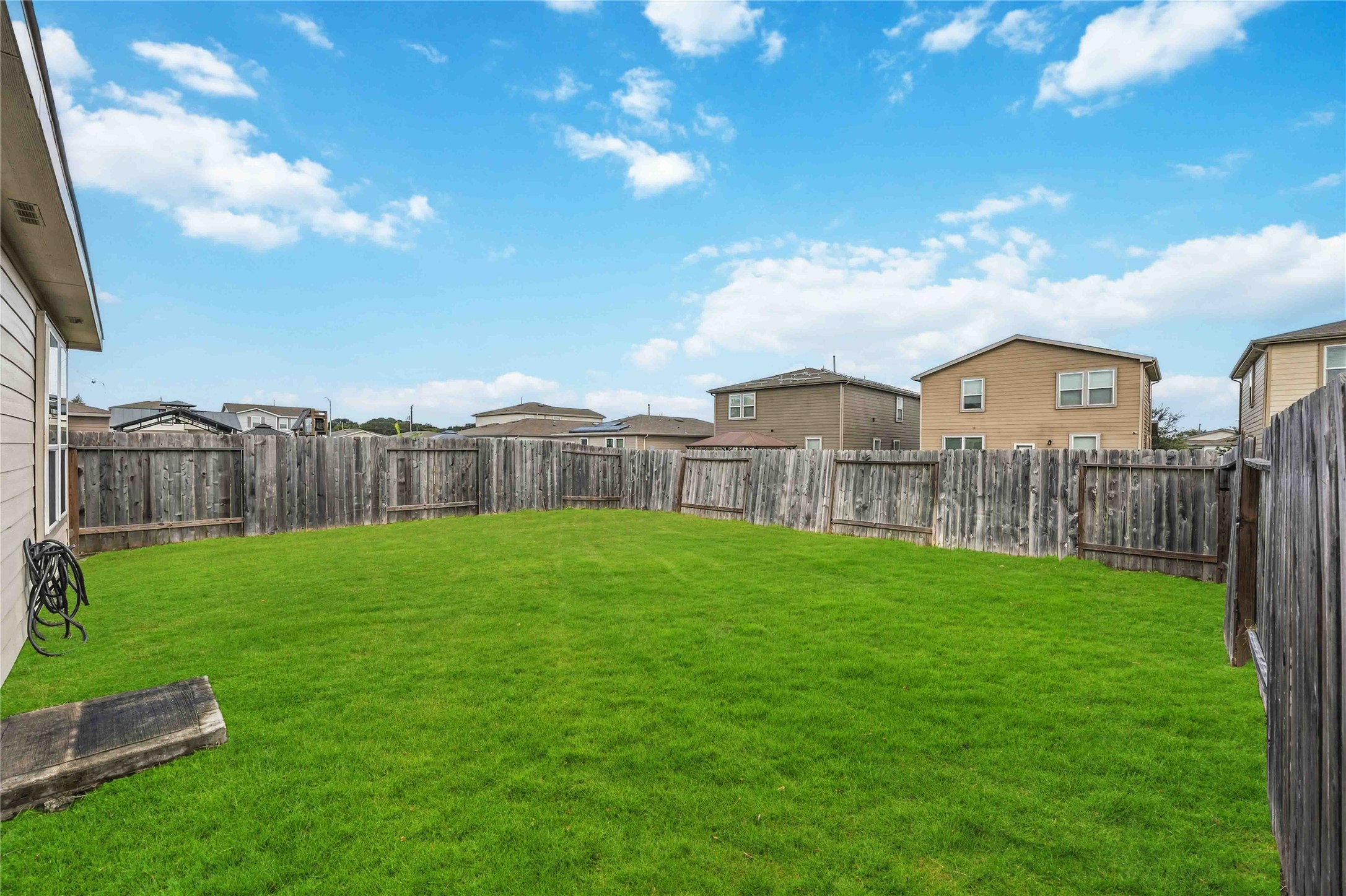Fenced backyard with an open lawn.