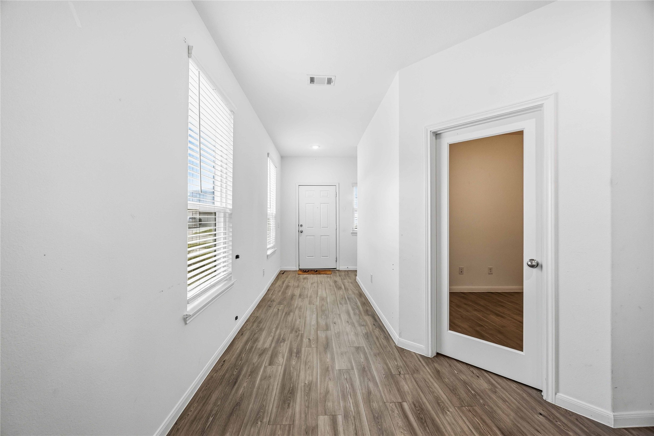 Welcoming entry hallway with wood-look flooring and a glass-paneled study door.