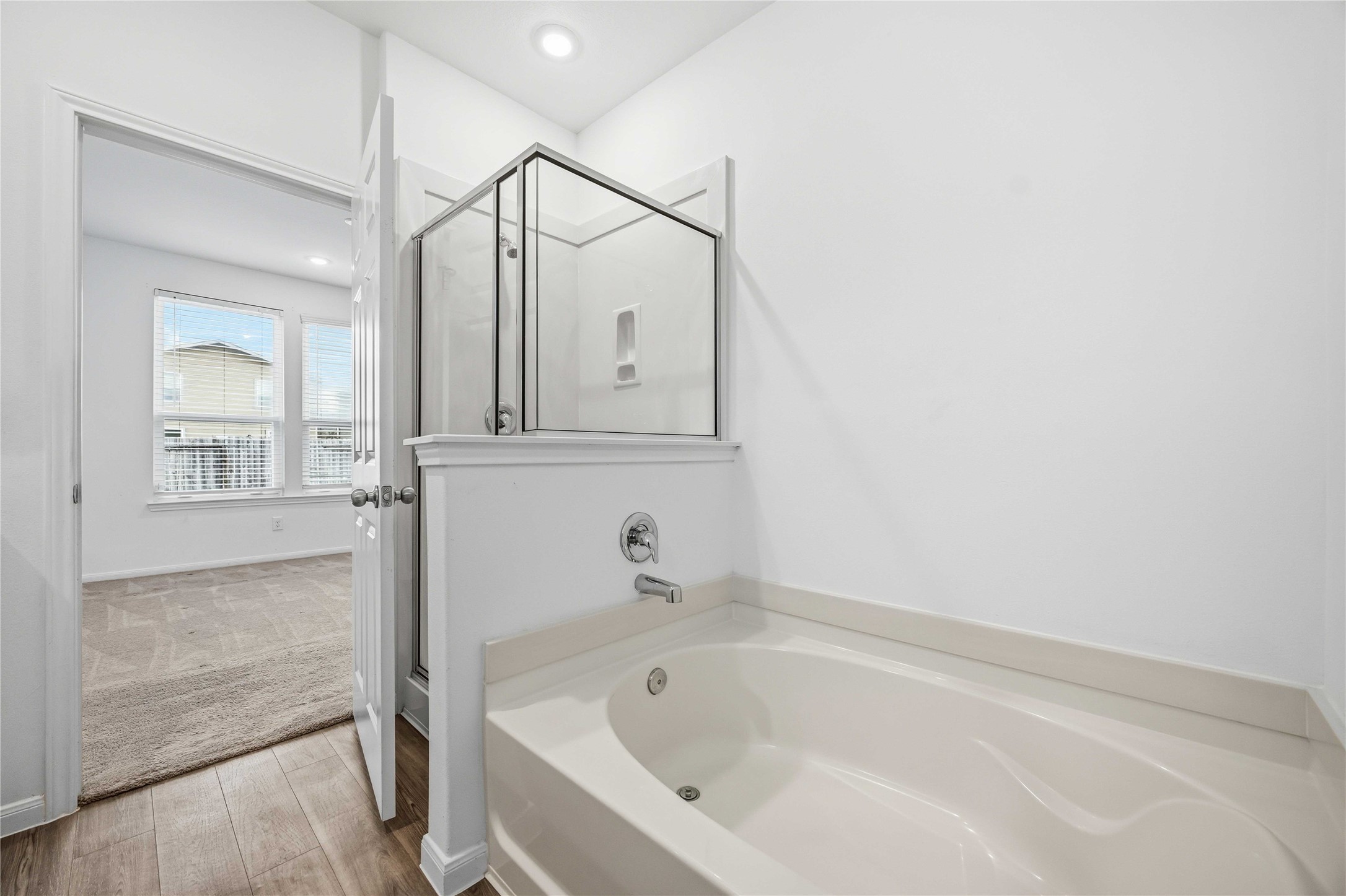 Primary bathroom featuring a soaking tub and separate glass-enclosed shower.