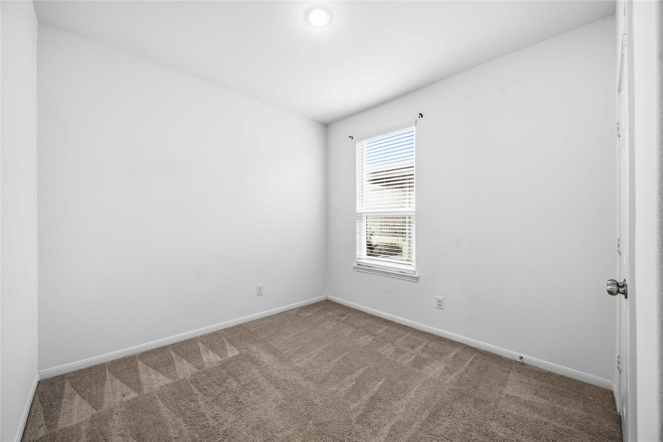 Secondary bedroom with carpeting and natural light.