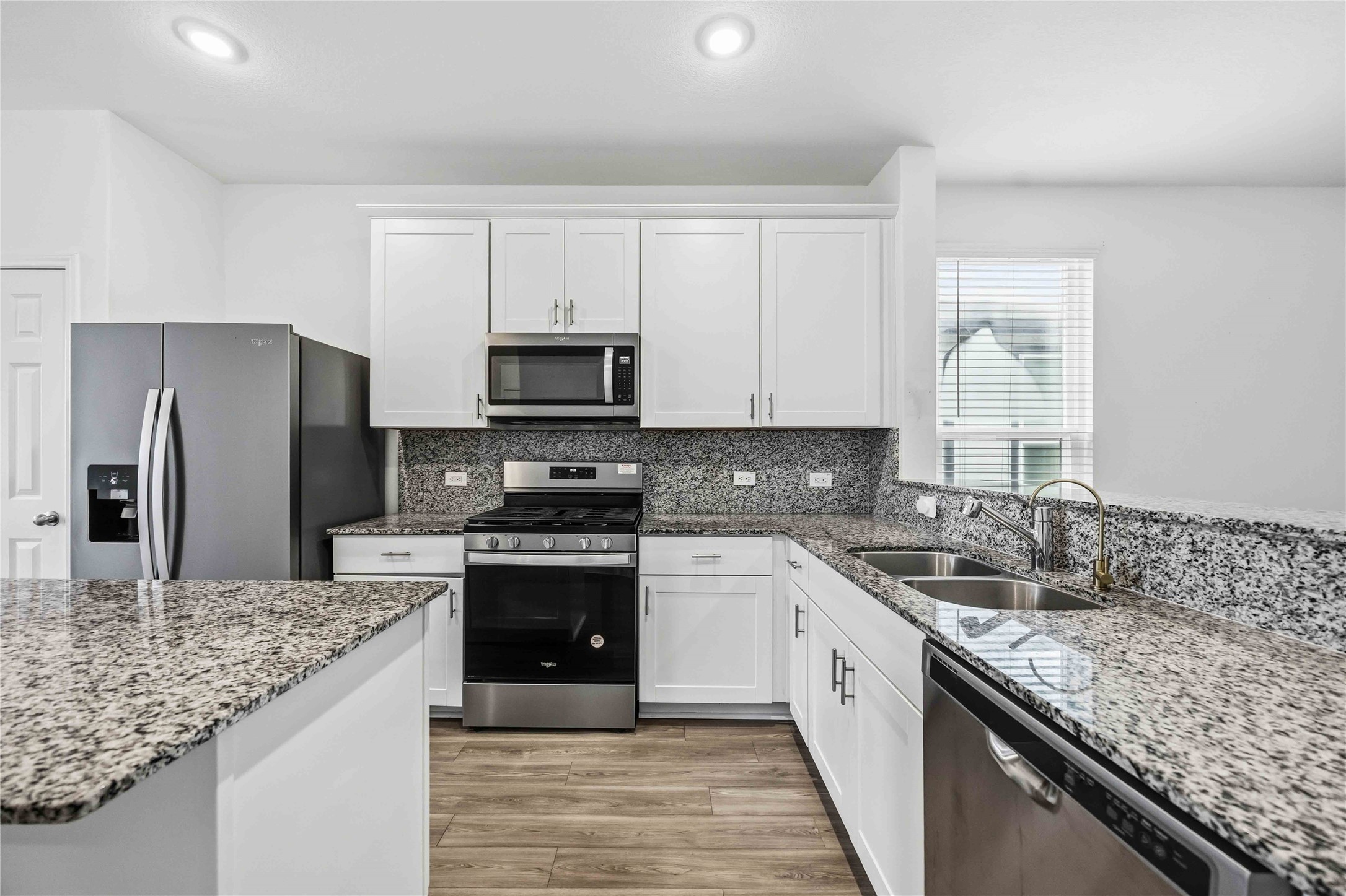 Stainless steel appliances complement granite countertops and backsplash.