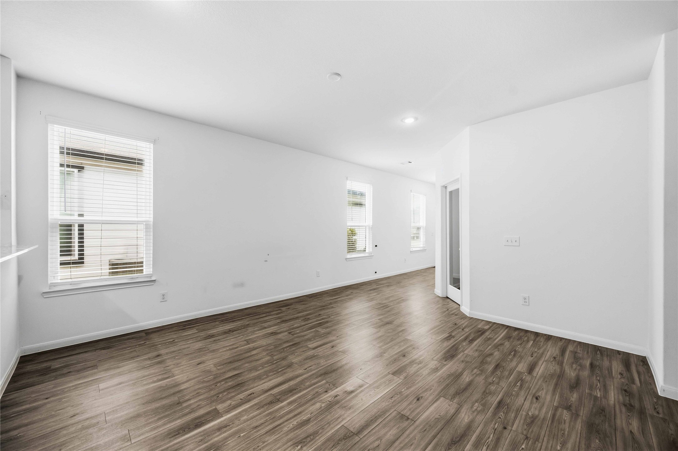 Bright living space with multiple windows and wood-look flooring.