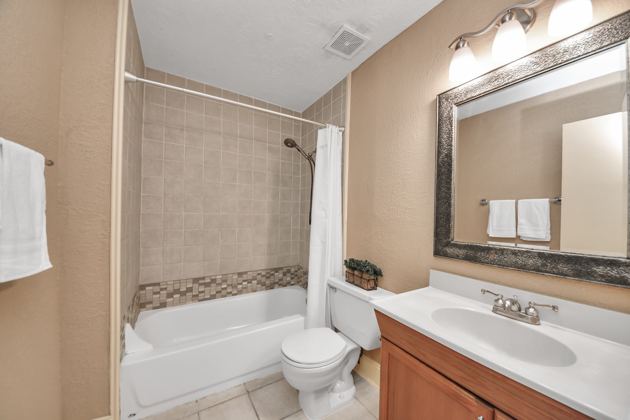 A tub-and-shower combination provides flexibility for daily routines, and the tile flooring offers a durable, easy-to-maintain surface. Conveniently located near the primary bedroom and main living areas, this bathroom is designed for everyday ease.