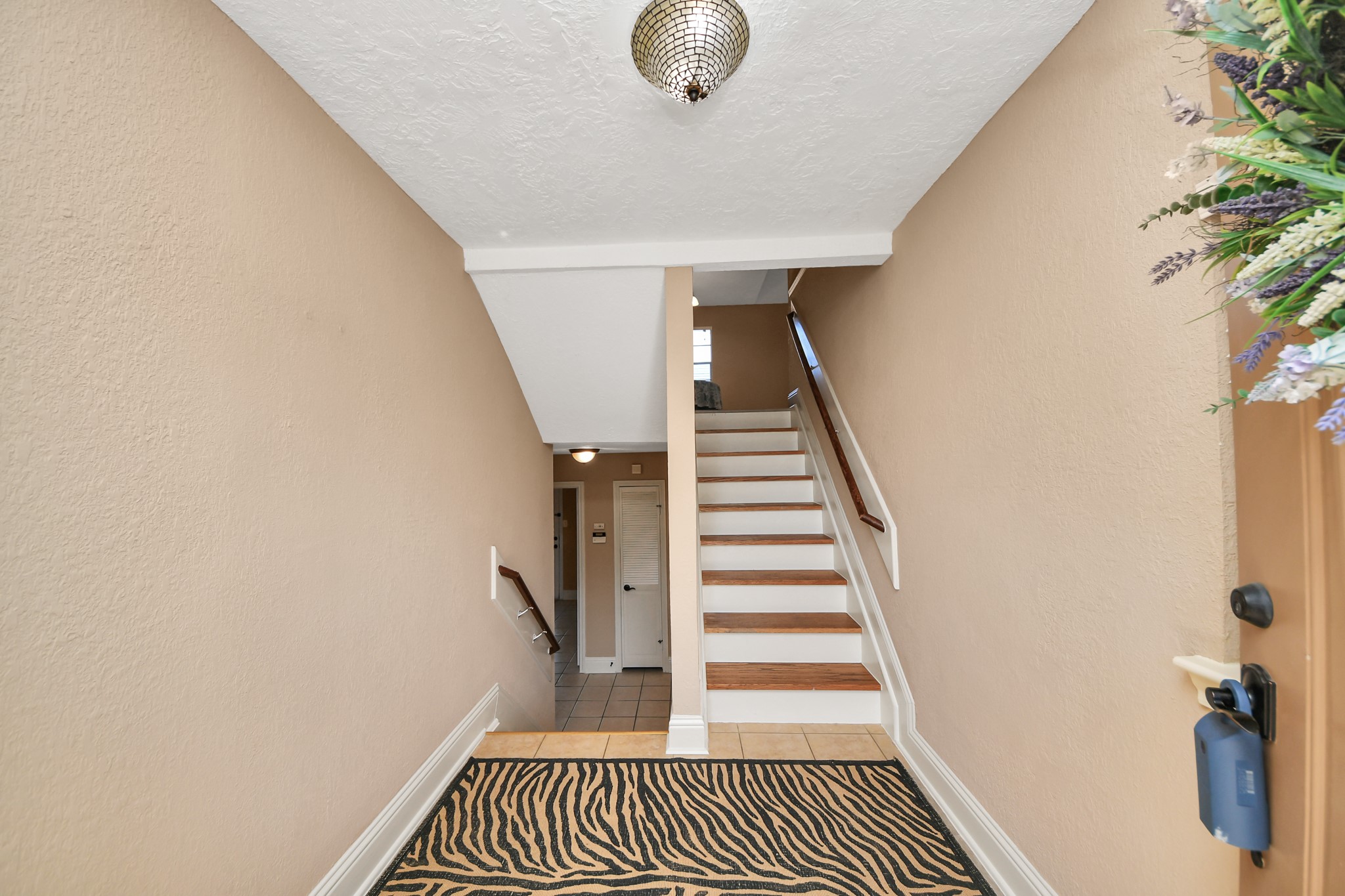 From the moment you enter, the distinctive split-level design introduces an appealing separation of living spaces. Wood-look stair treads, contrasting white risers, and traditional handrails create architectural interest, while the entryway provides access to both the upper and lower levels. This thoughtful configuration offers flexibility and a sense of separation between the home's gathering areas and additional rooms.