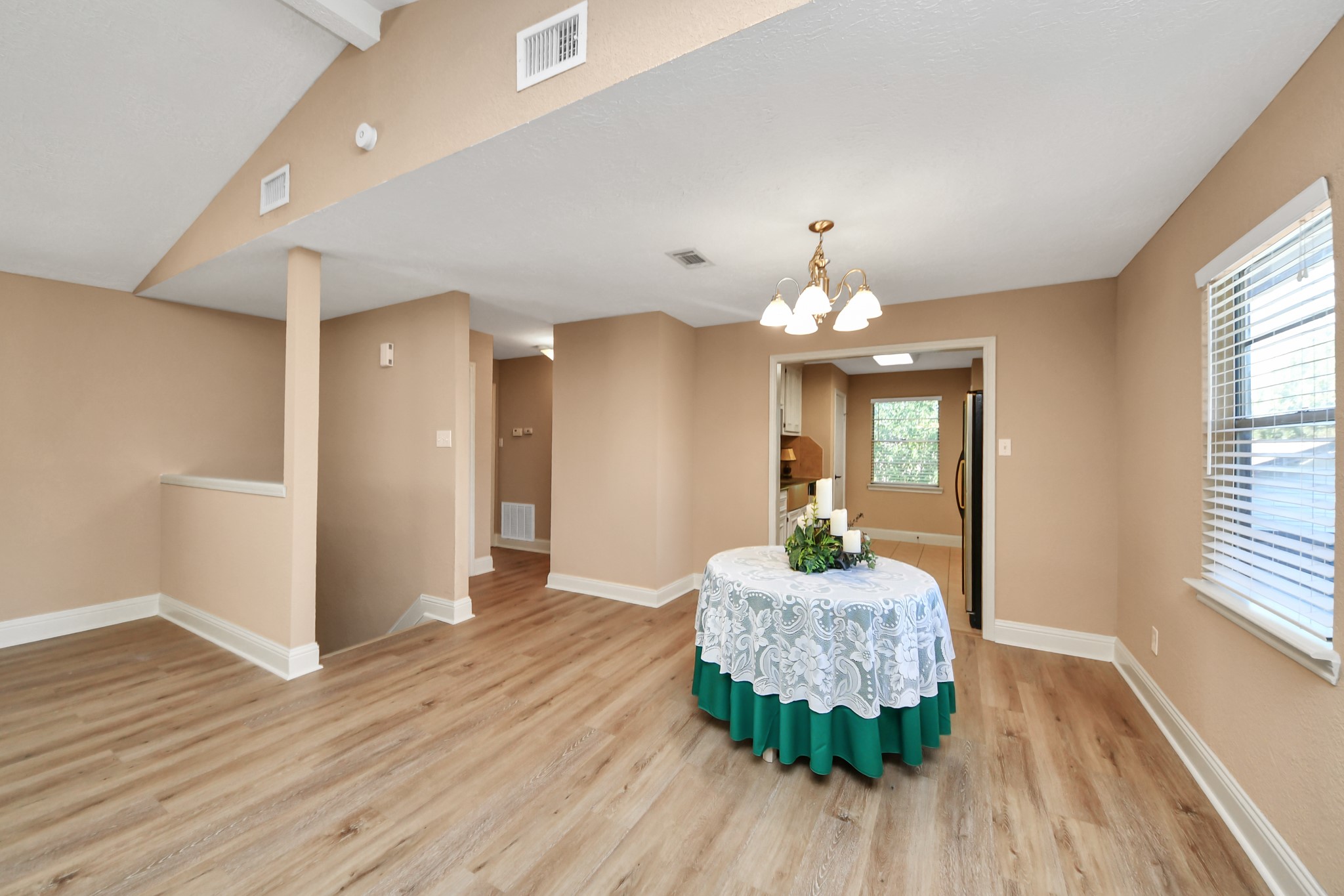 Whether enjoying a quiet morning coffee or hosting a festive dinner, this versatile dining area provides the perfect setting. Featuring attractive wood-look flooring, a traditional chandelier, and a window welcoming natural light, the space flows conveniently into the kitchen, making serving meals and entertaining guests effortless.