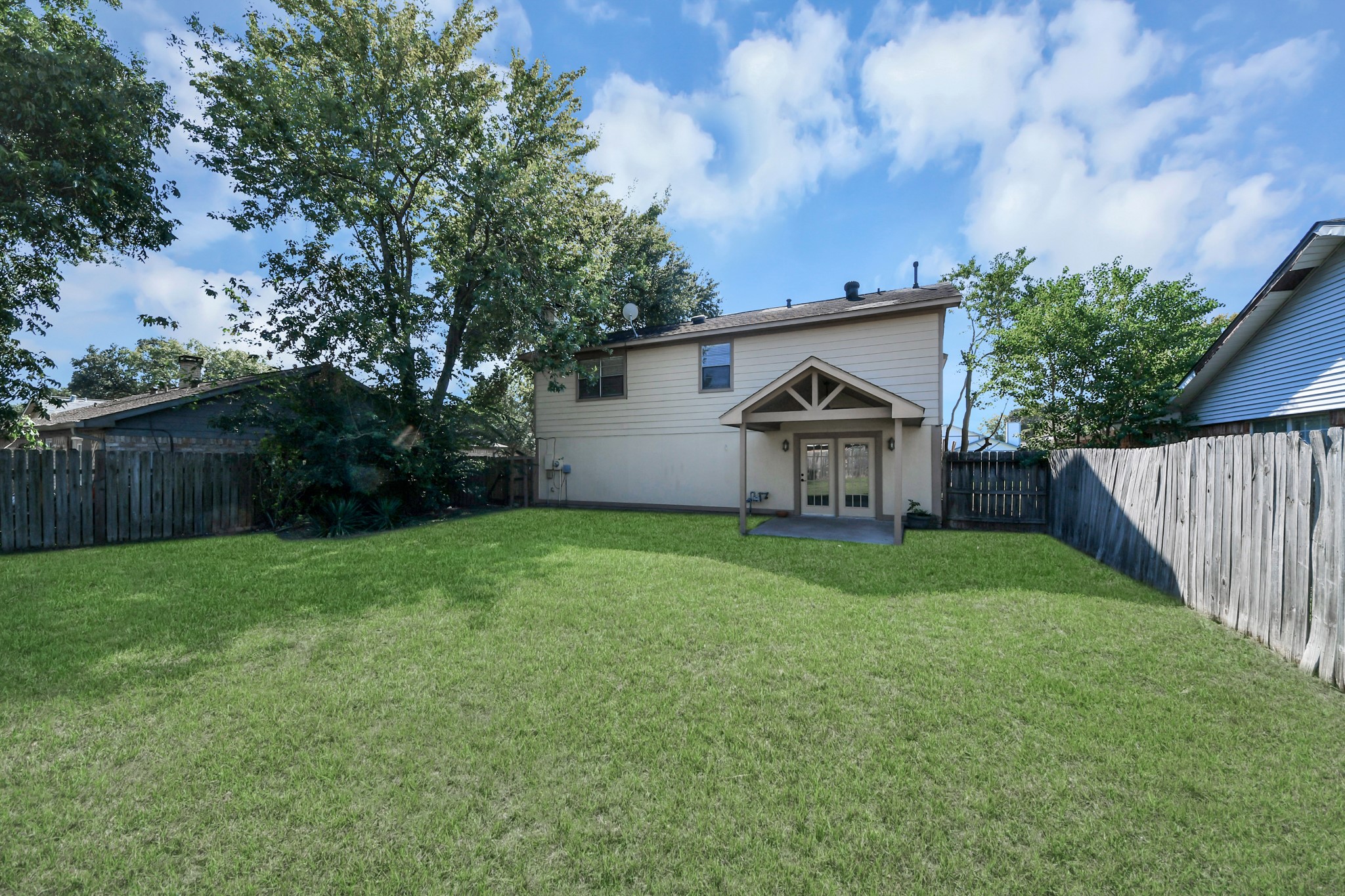 The expansive grassy lawn provides plenty of space for outdoor games, pets to roam, gardening, or even a future playset. The covered patio, complete with a ceiling fan, creates an inviting spot to enjoy your morning coffee, dine outdoors, or unwind after a long day