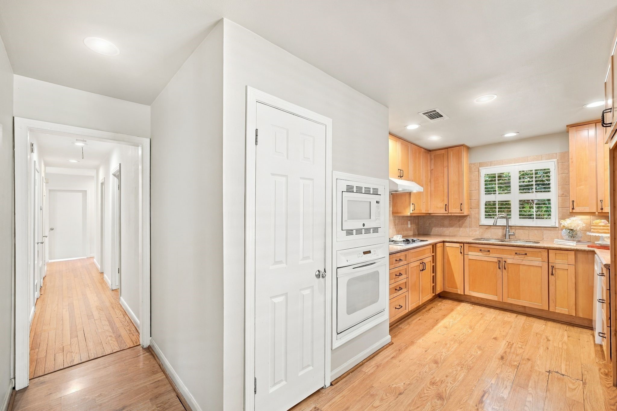View of hallway from kitchen. Storage closet on left side of hallway and bedrooms on right