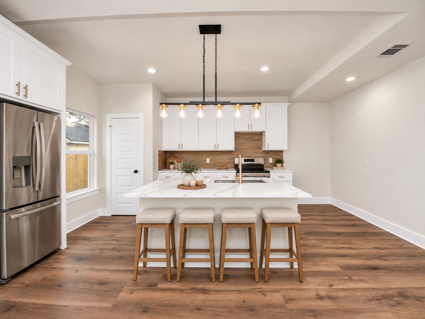 Beautifully appointed kitchen featuring quartz countertops, white soft-close cabinetry, stainless steel appliances, stylish pendant lighting & a generously sized center island with bar seating.