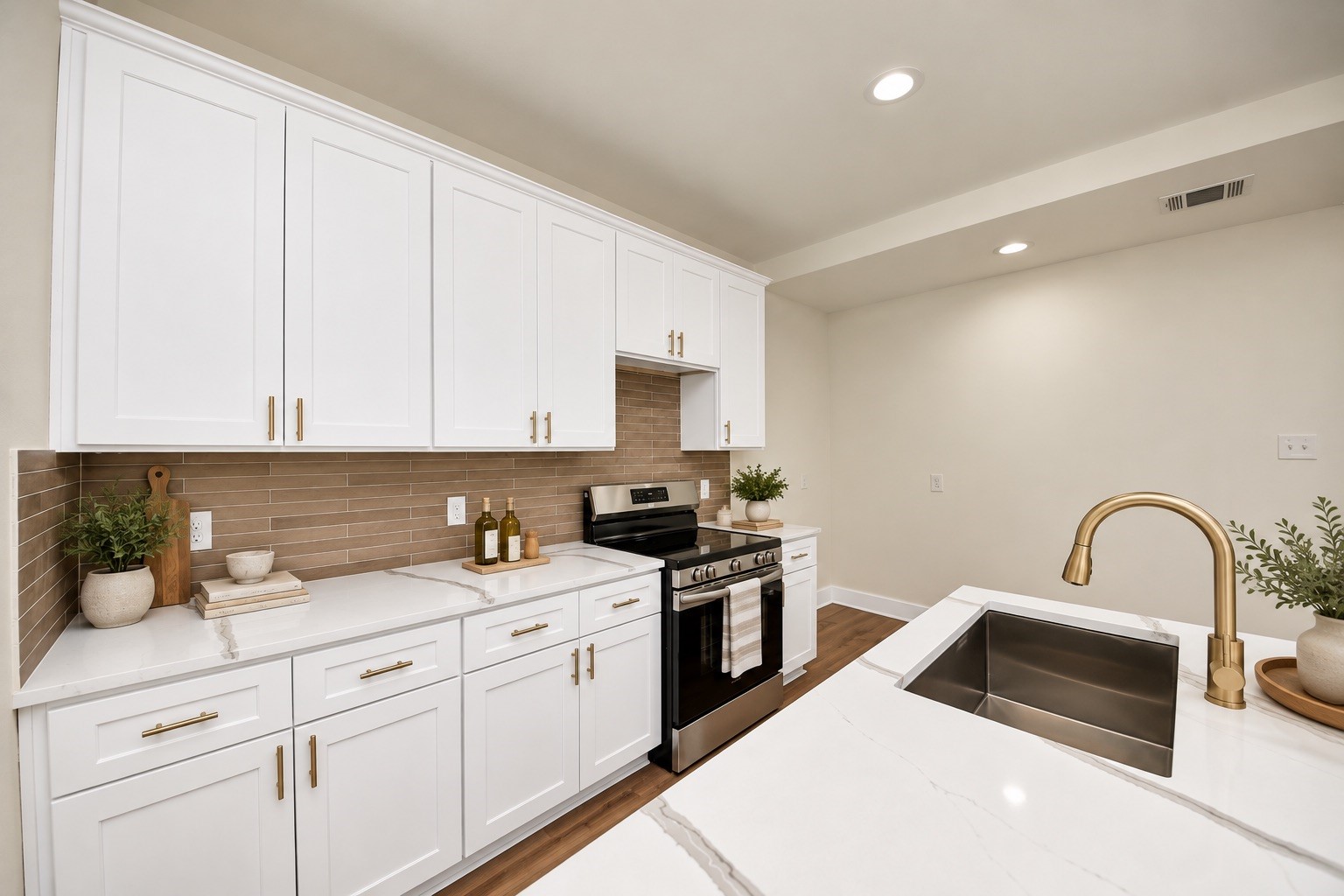 Detailed view showcasing white cabinetry with sleek modern hardware pulls, decorative tile backsplash, quartz countertops, stainless steel appliances & ample cabinet storage.