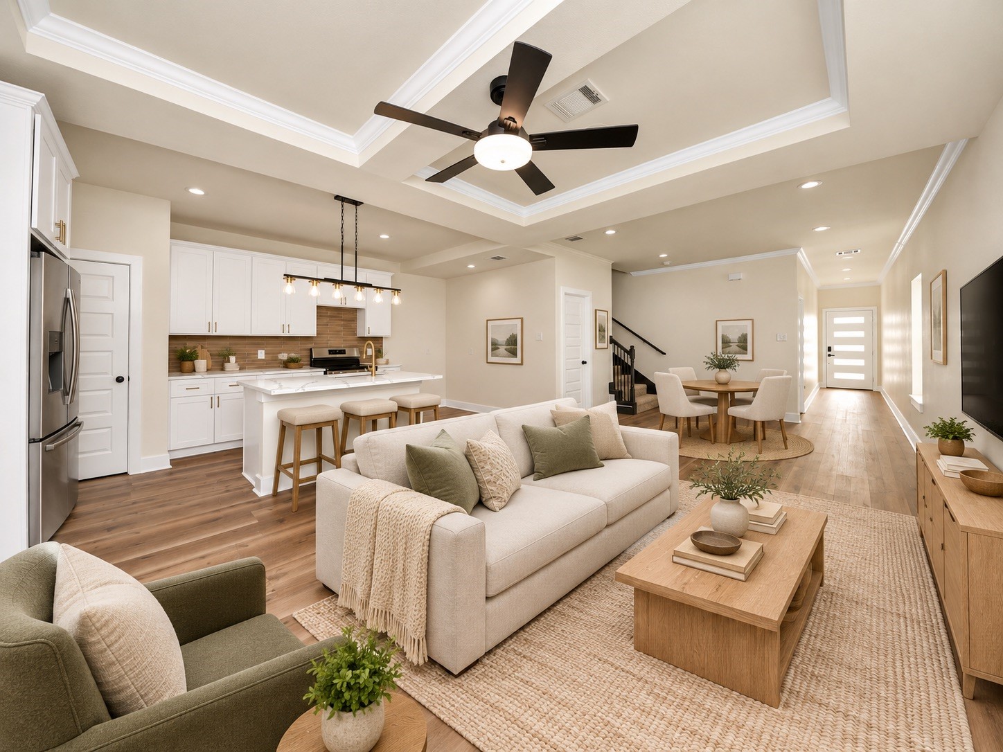 Another view of the spacious living area highlighting the beautiful flooring, crown molding, tray ceilings & seamless connection between the kitchen, dining & living spaces | Virtually staged