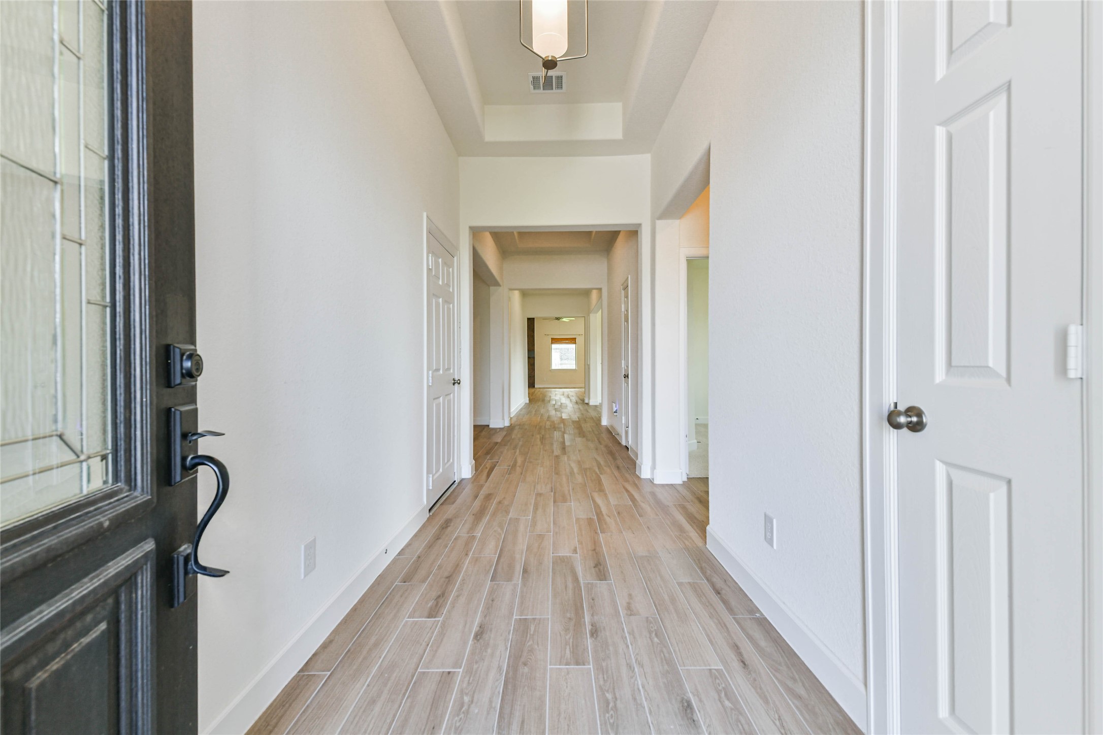Step into a bright and inviting hallway with elegant wood-look tile flooring, leading to spacious living areas.