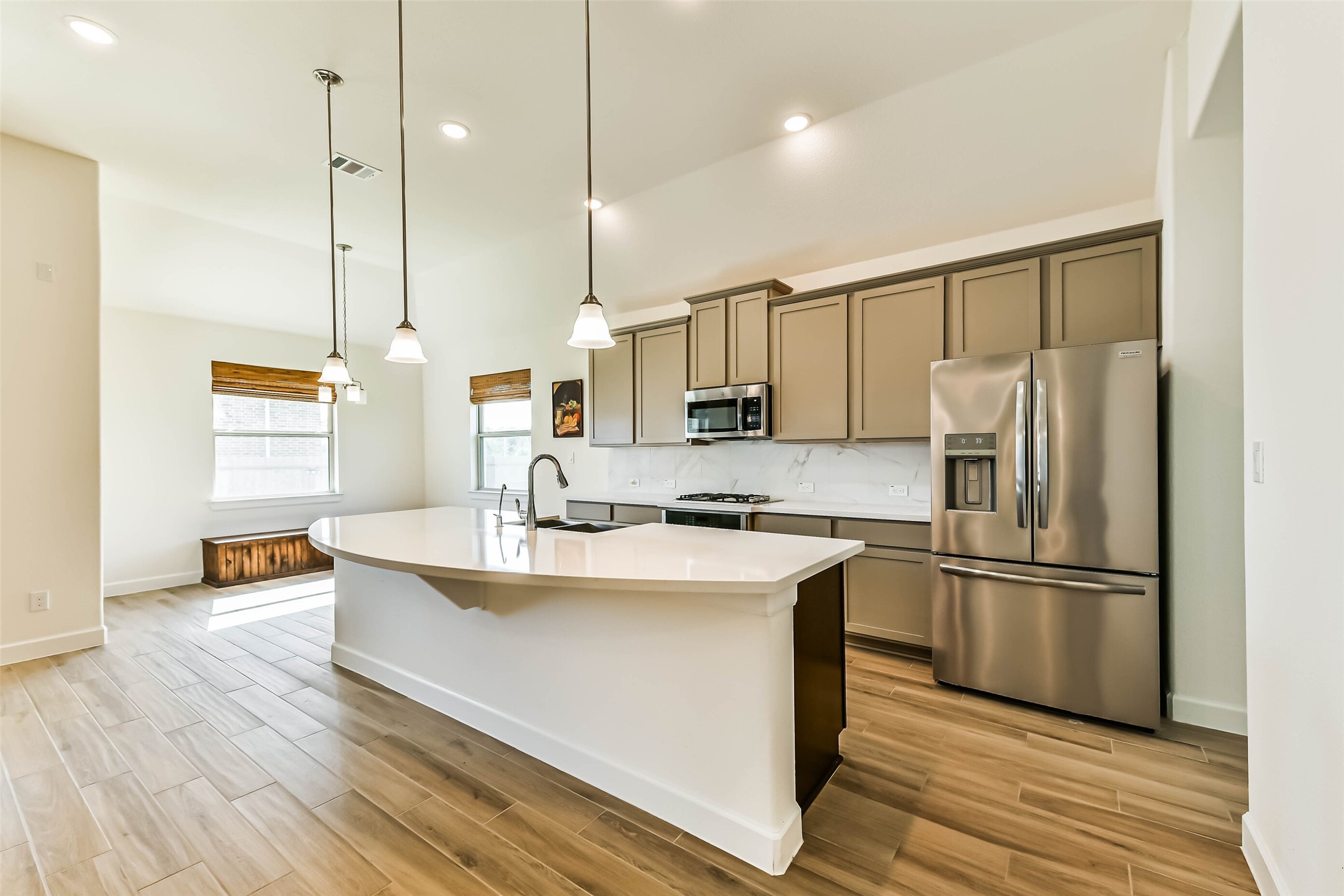 Bright, modern kitchen featuring a sleek island with pendant lighting, stainless steel appliances, and ample cabinet space, seamlessly connected to an inviting dining area with natural light.