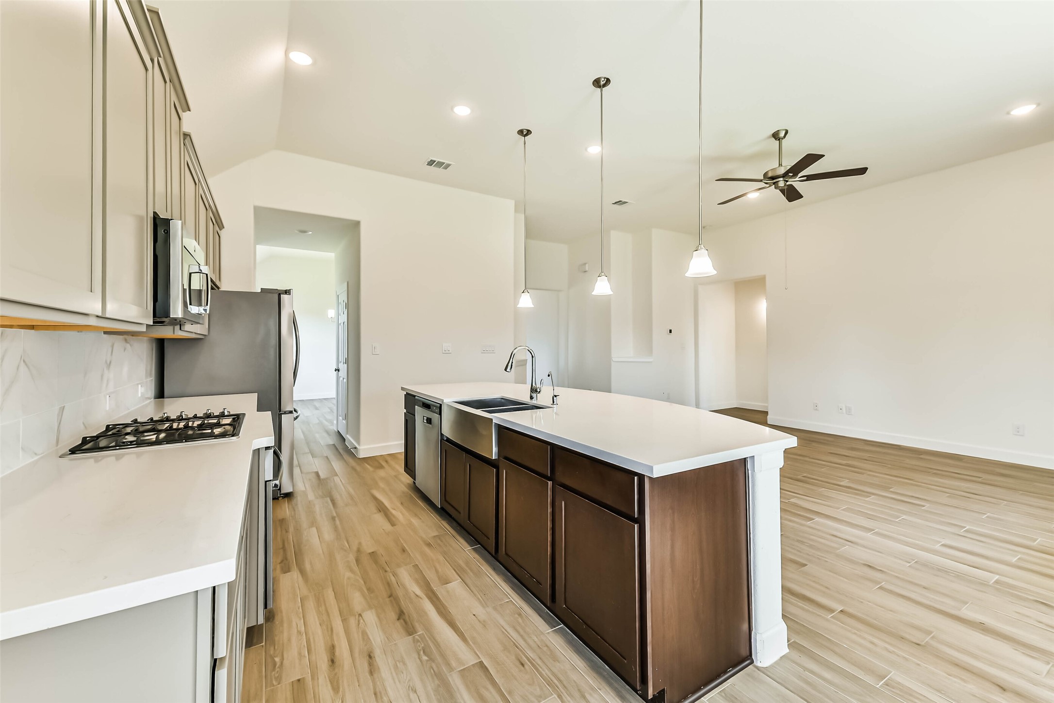 Modern kitchen with sleek countertops, stainless steel appliances, and an open layout flowing into a spacious living area with high ceilings and stylish lighting.