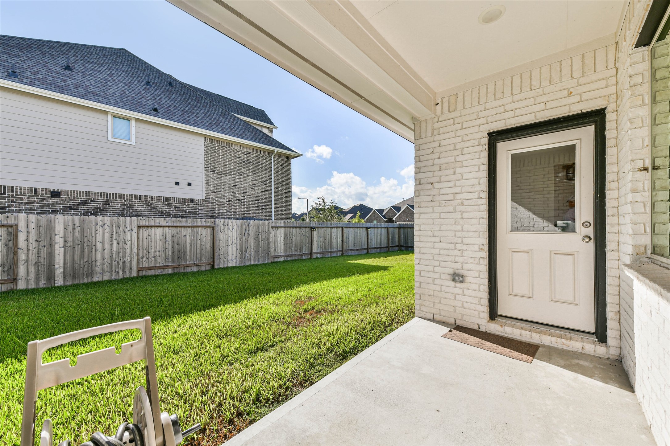 Charming covered patio overlooking a lush, fenced backyard, perfect for outdoor relaxation and entertaining.