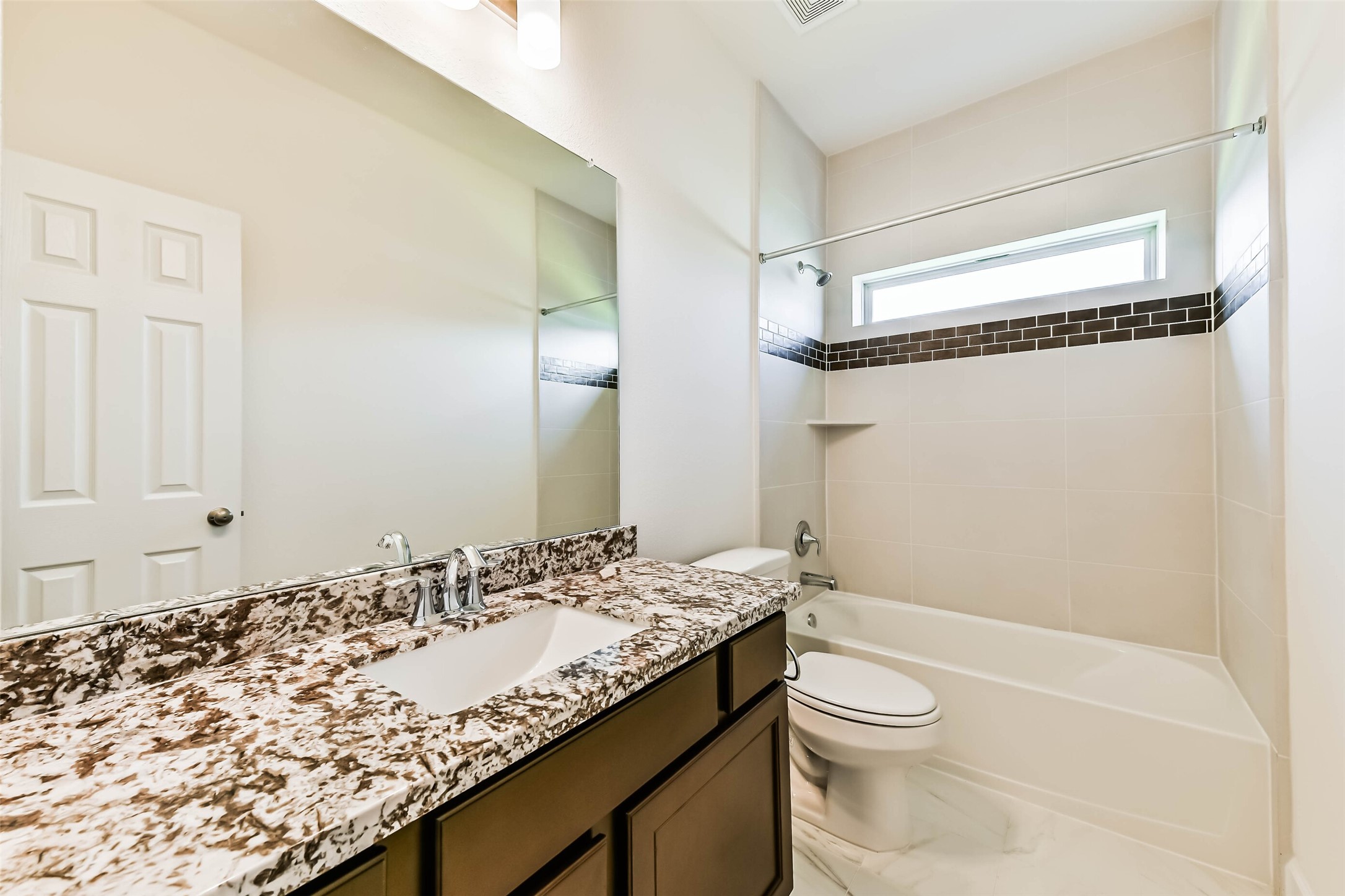 Seccondary Modern bathroom #2 featuring a sleek granite countertop, elegant fixtures, and a stylish tiled bathtub with accent trim.