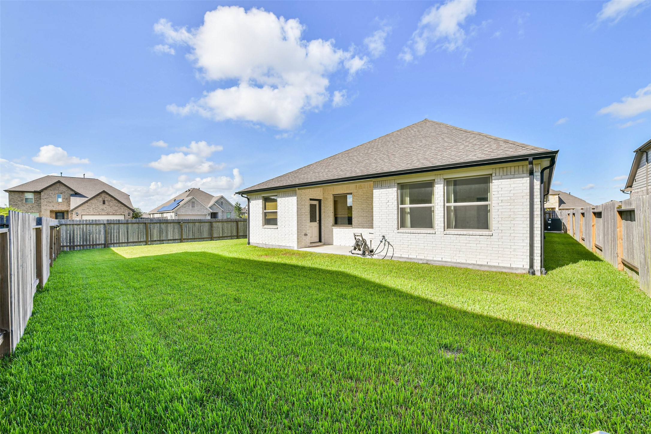 Charming backyard featuring a spacious lawn, perfect for outdoor activities, enclosed by a wooden fence for privacy.