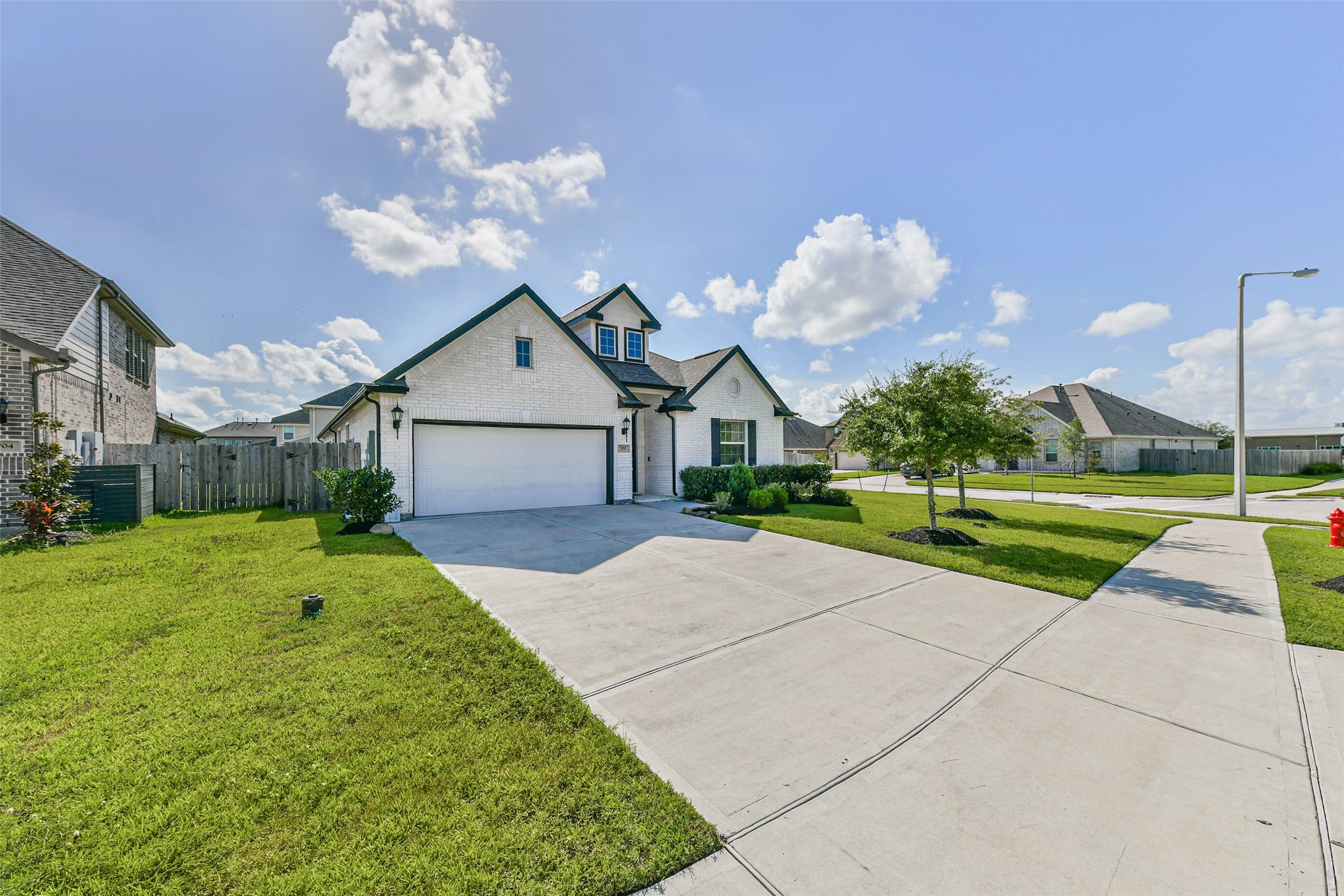 Charming one-story home on a spacious corner lot, featuring a well-maintained lawn and an inviting driveway leading to a two-car garage.