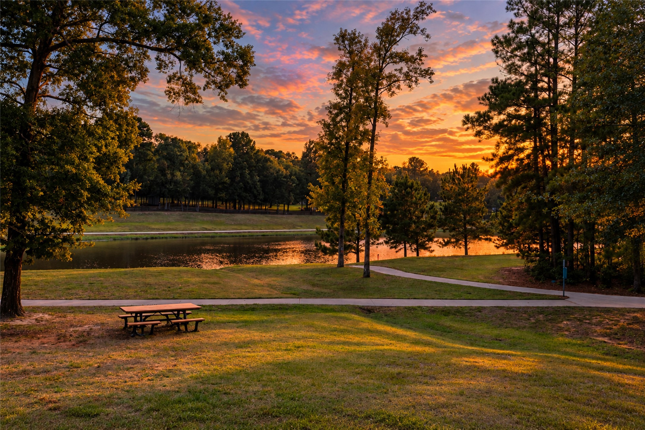 A community lakeside setting with a walking path and picnic table offers a peaceful place to pause.