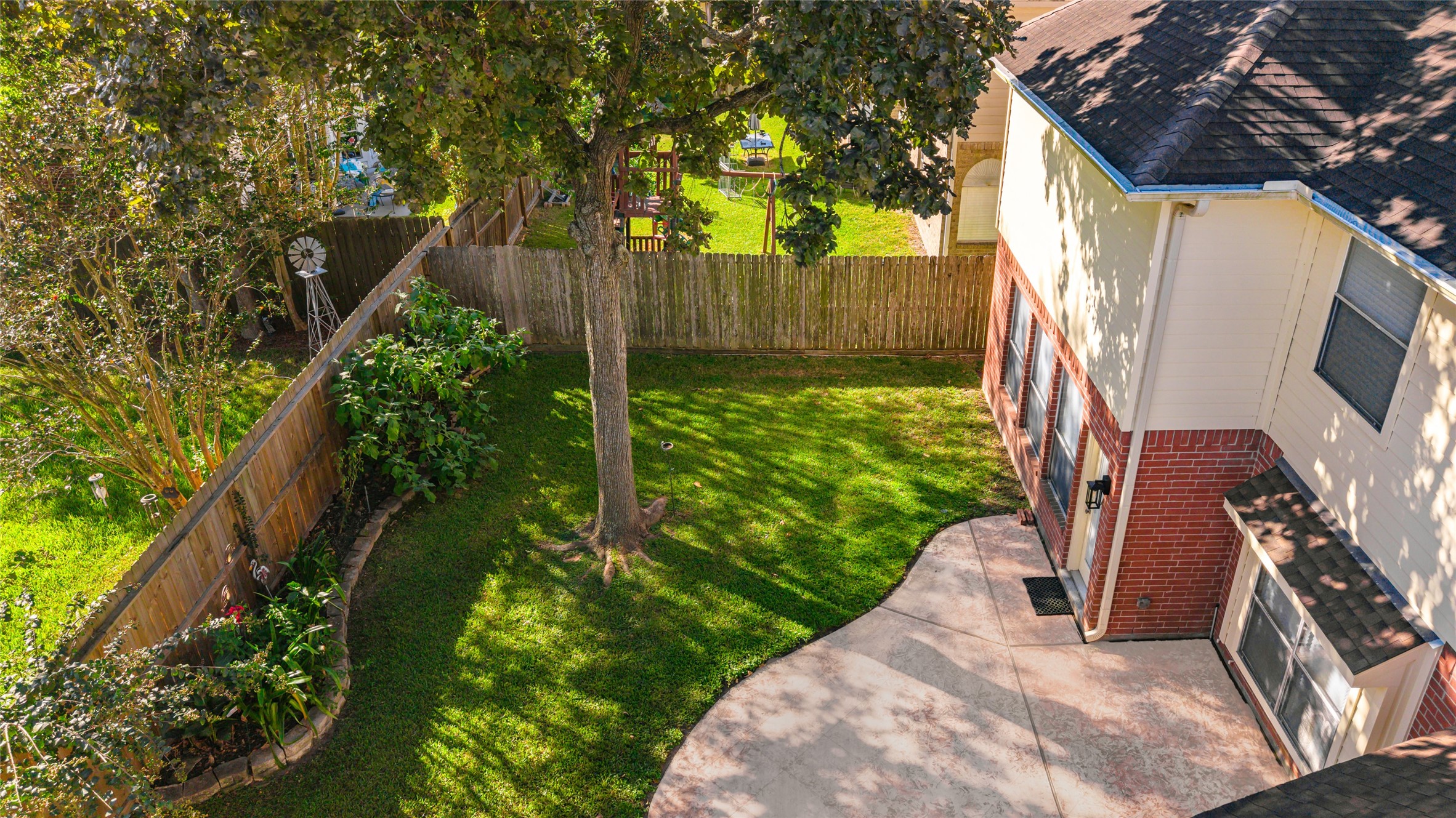 Spacious backyard with a mix of lush greenery and a well-maintained lawn, complemented by a charming patio area perfect for outdoor relaxation.