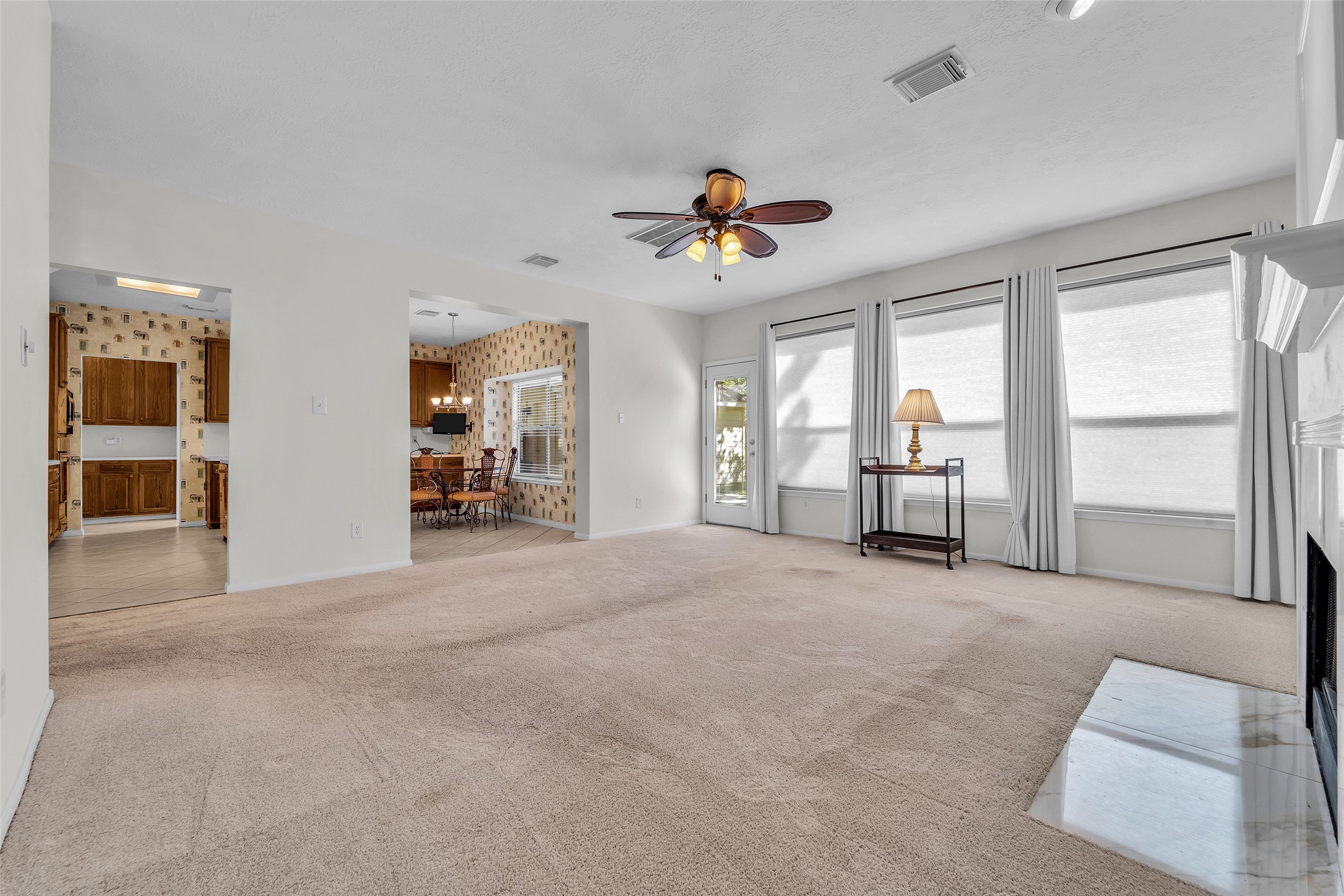 Spacious living area with abundant natural light, a cozy fireplace, and an adjacent dining space leading to a charming kitchen.