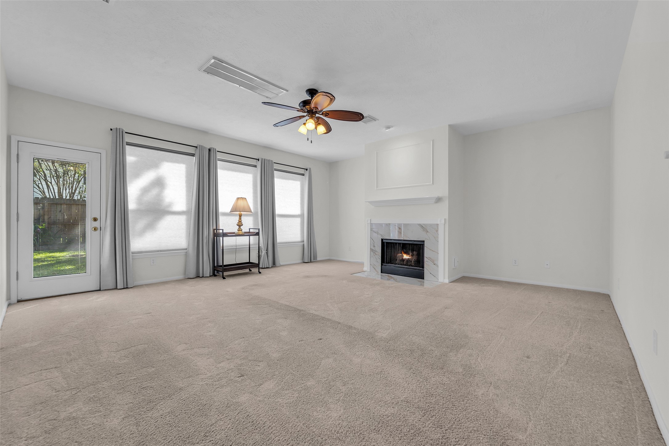 Spacious living room featuring a cozy fireplace, large windows for natural light, and direct access to the outdoor space through a glass door.