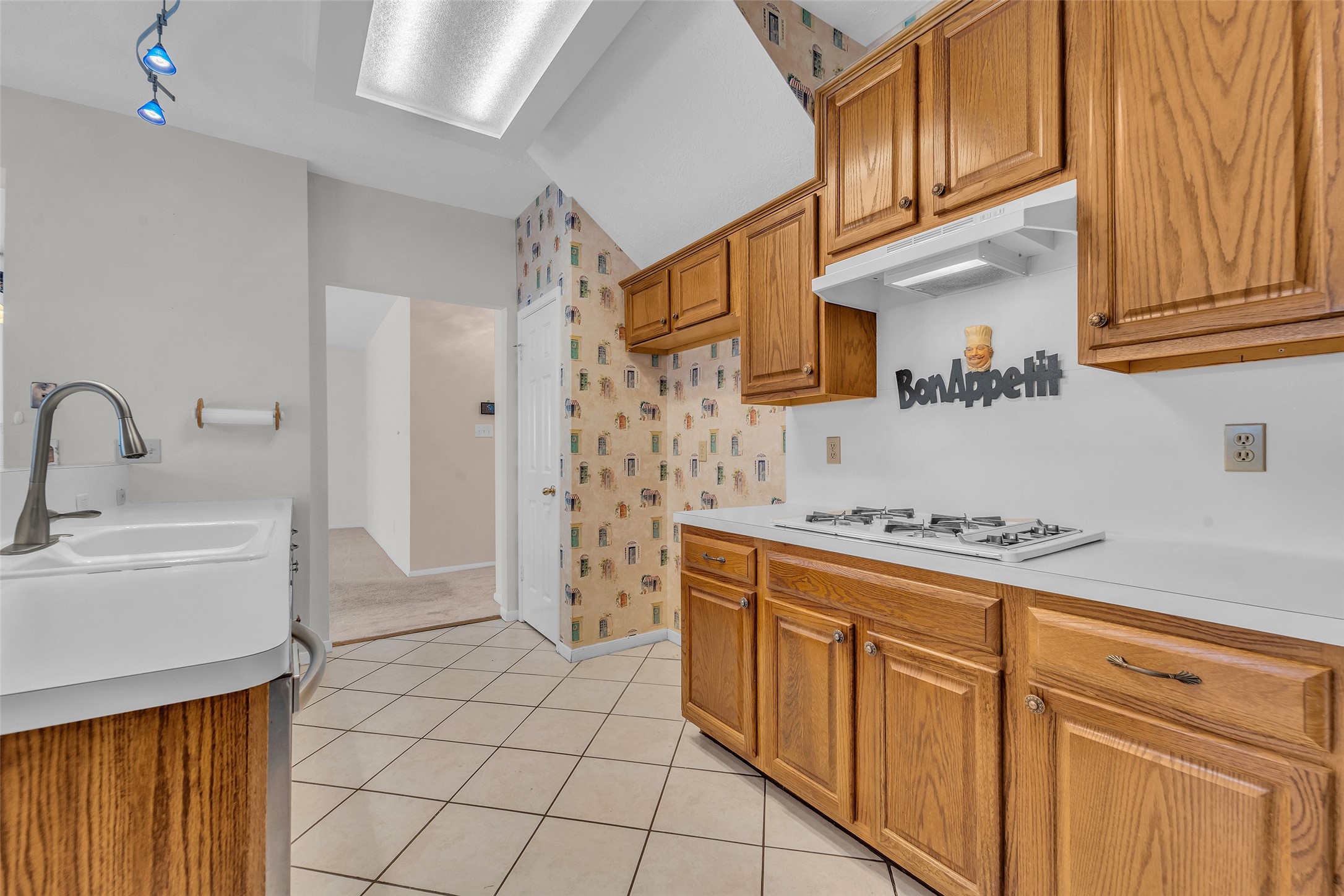 Cozy kitchen with warm wooden cabinetry, a gas cooktop, offering a welcoming atmosphere for culinary adventures.