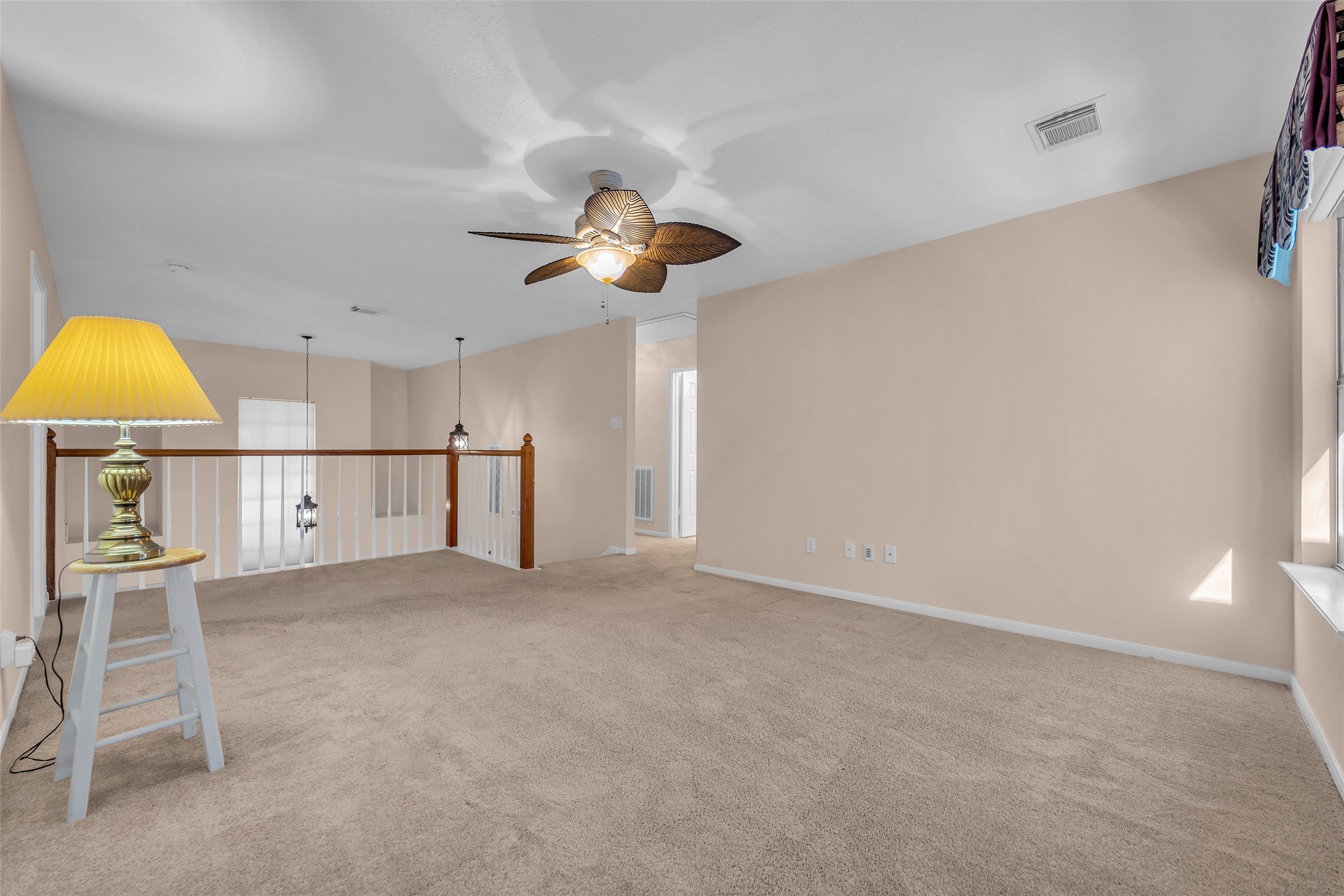 Spacious upstairs area with soft carpet, neutral walls, and a stylish ceiling fan, offering a cozy and versatile living space.