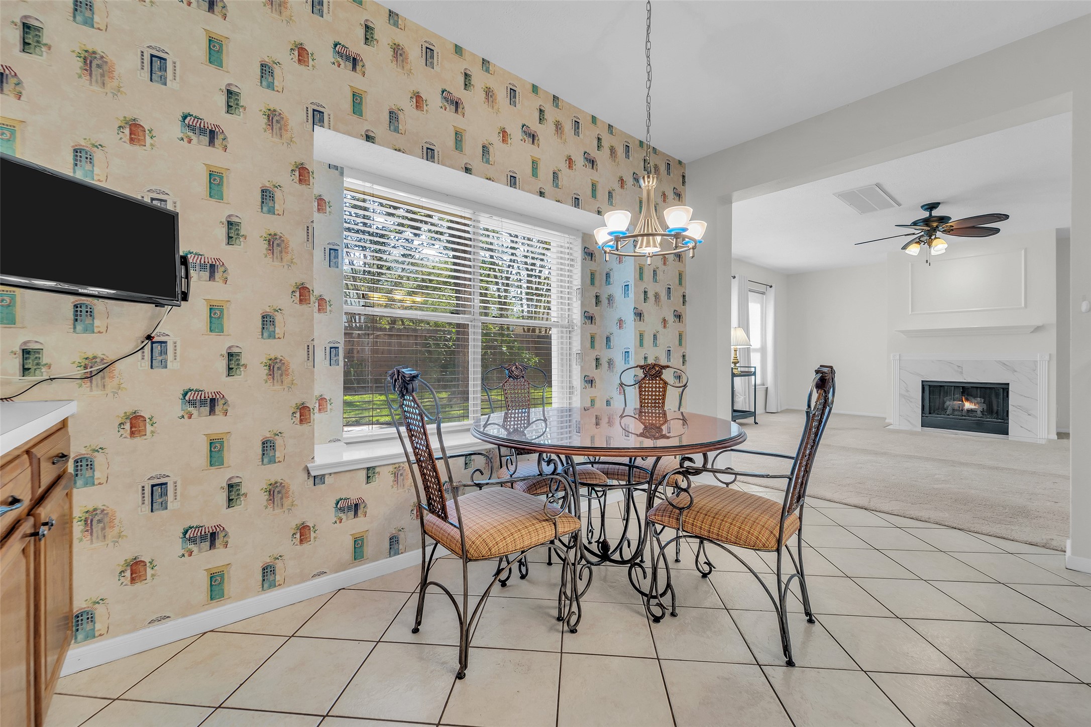 Charming dining area with natural light, adjacent to a cozy living room featuring a fireplace and ceiling fan.