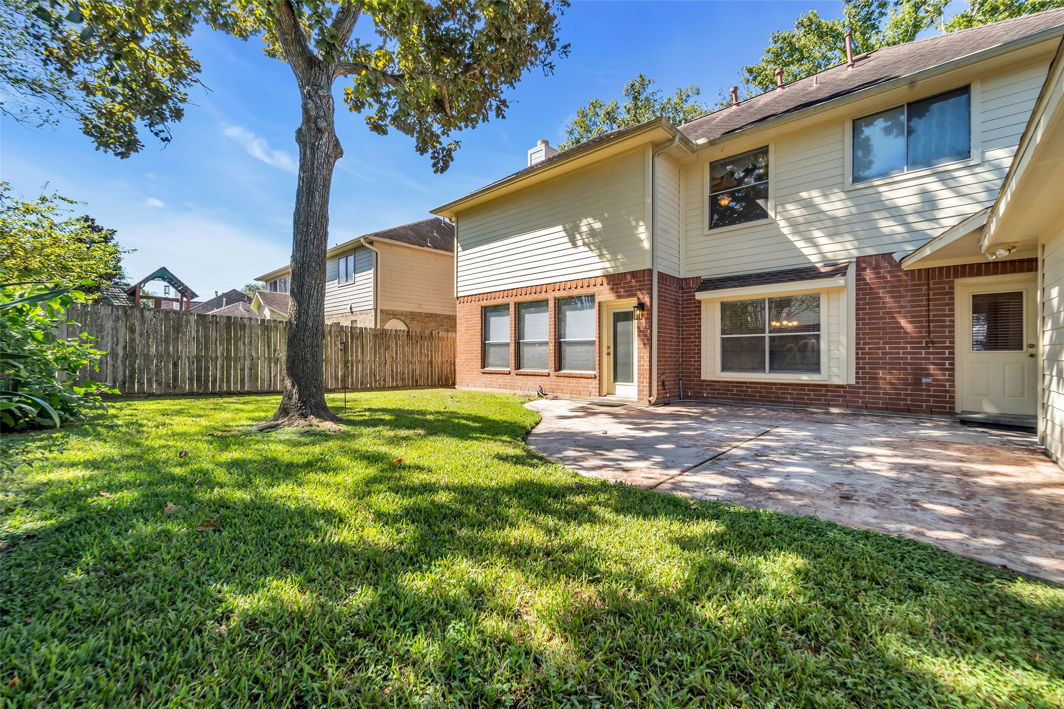 Spacious backyard with a charming patio, perfect for outdoor gatherings, surrounded by lush greenery and mature trees for added privacy.