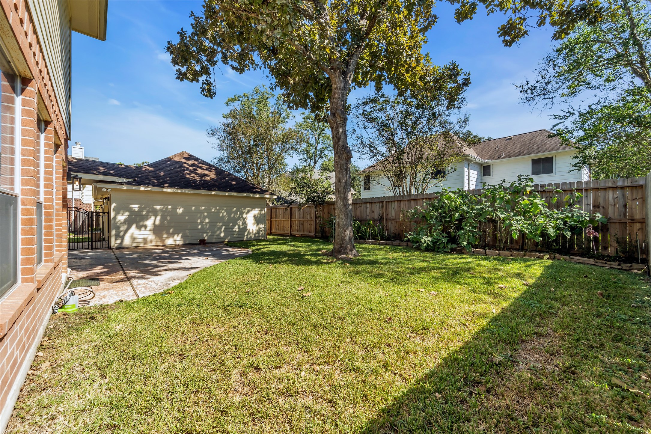 Charming backyard featuring a lush green lawn, a mature tree providing shade, and a well-maintained wooden fence for privacy, perfect for outdoor relaxation.