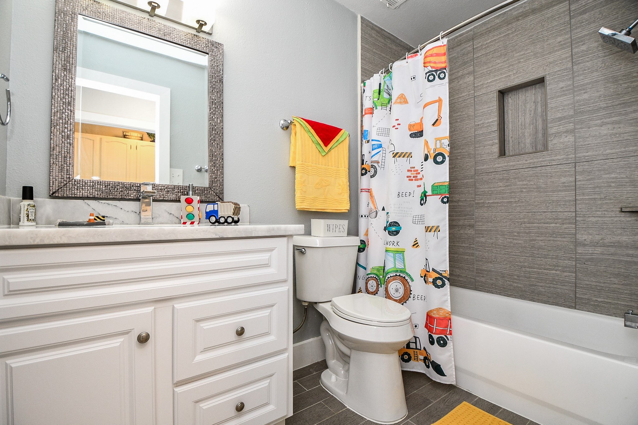 The secondary bath has a white vanity and a tub/shower combo with a modern tile surround and built-in niche.