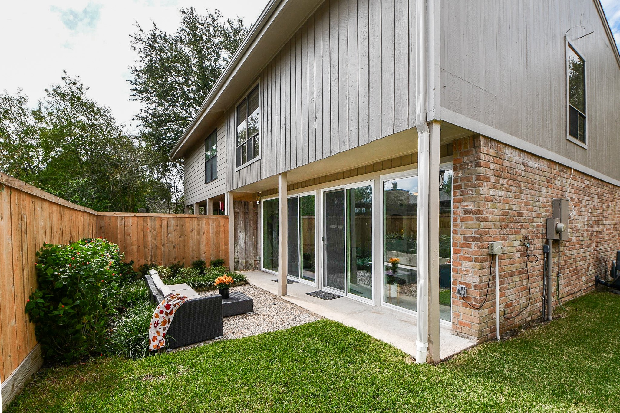 The fenced backyard has a lush lawn and mature landscaping, and the two-story rear wall is lined with glass.