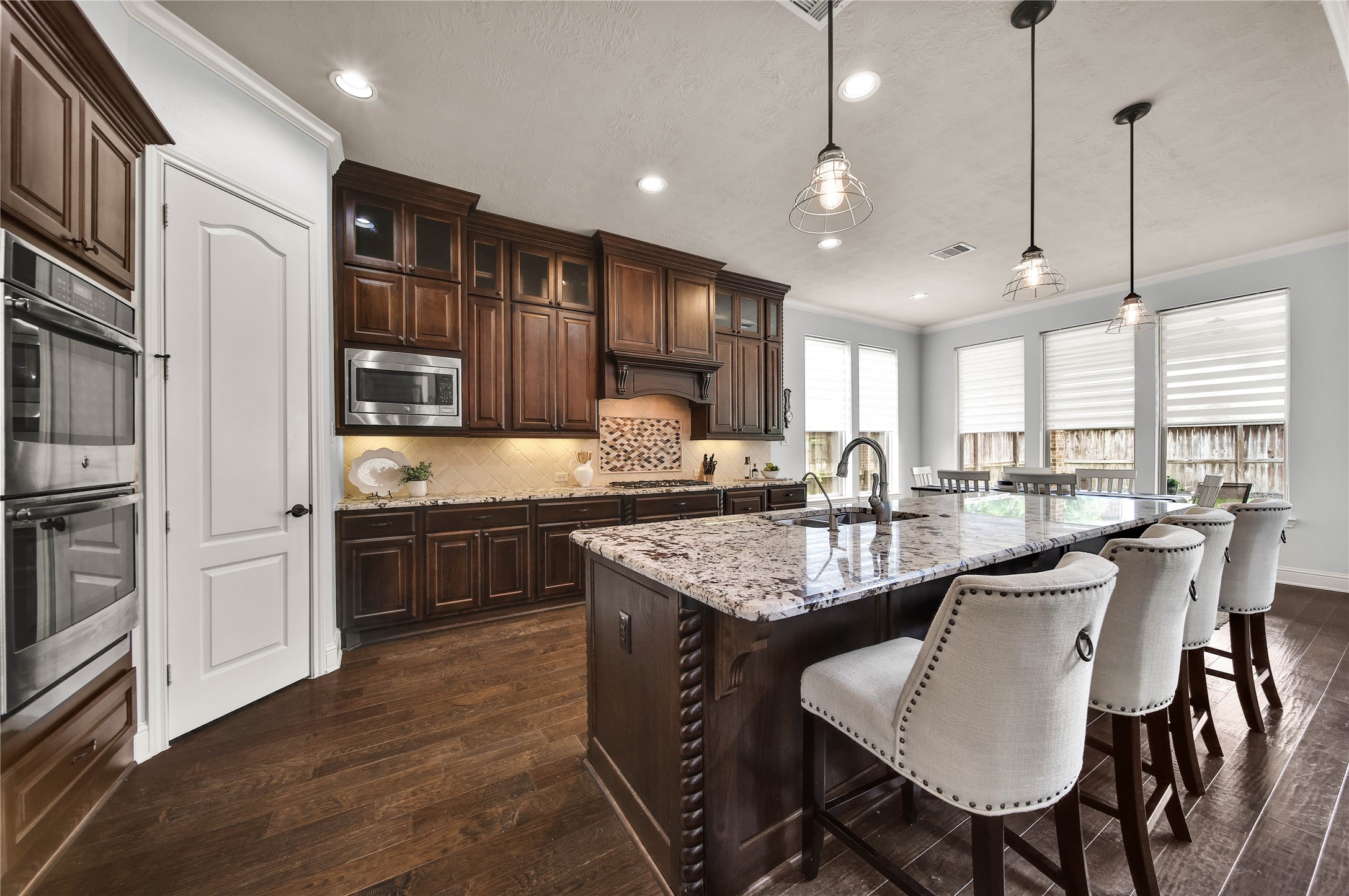 The cabinetry and detailed trim work throughout the kitchen are simply beautiful, adding a touch of elegance and craftsmanship to the space. The cabinets extend all the way to the ceiling, featuring glass-front doors across the top row for a sophisticated display and elevated design.