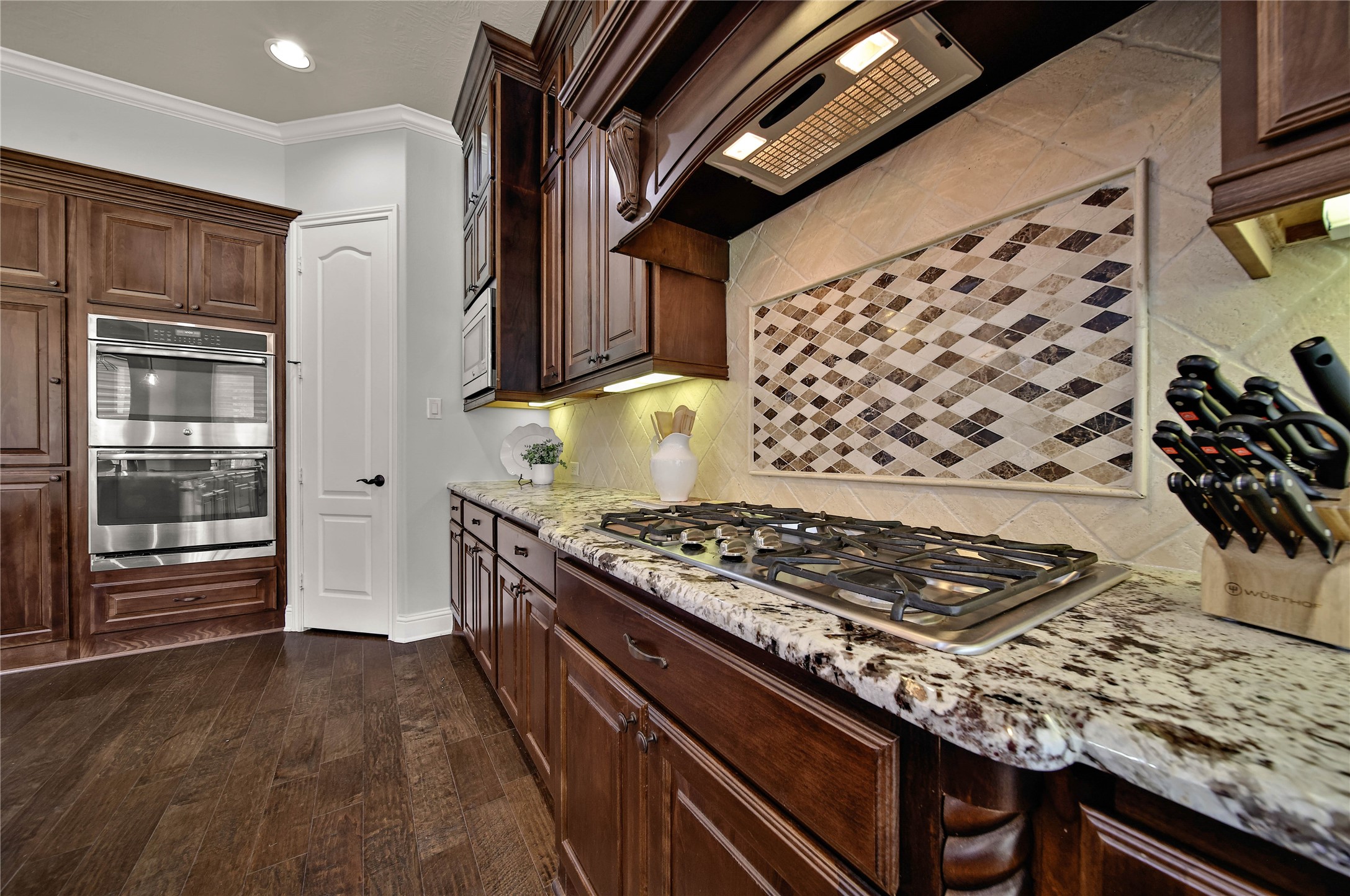 The kitchen boasts exotic granite countertops and tumbled travertine backsplashes, highlighted by a stunning mosaic design above the cooktop that adds a unique touch of elegance and character.