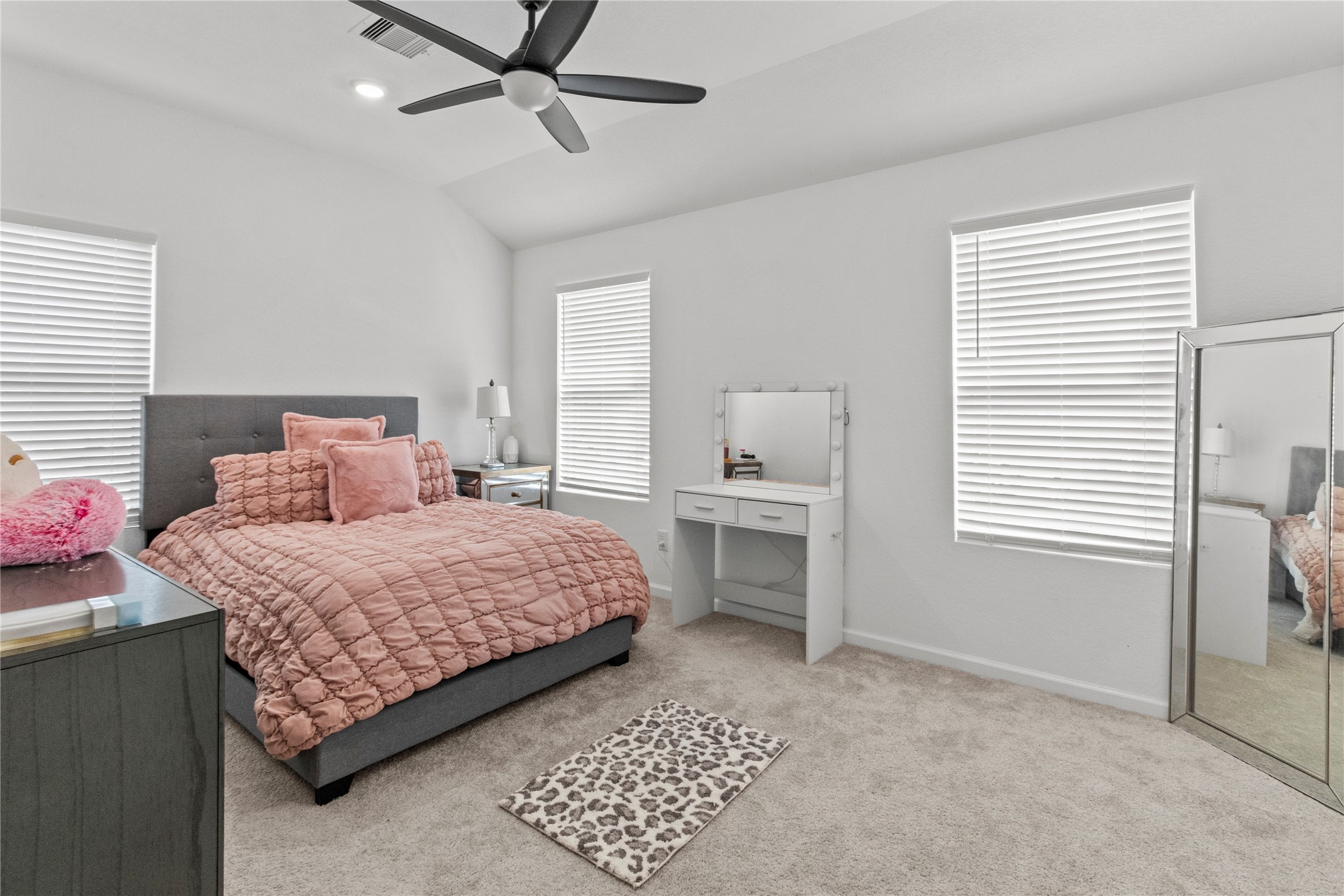 Bright and inviting bedroom with ample natural light from two windows, while the ceiling fan ensures comfort.