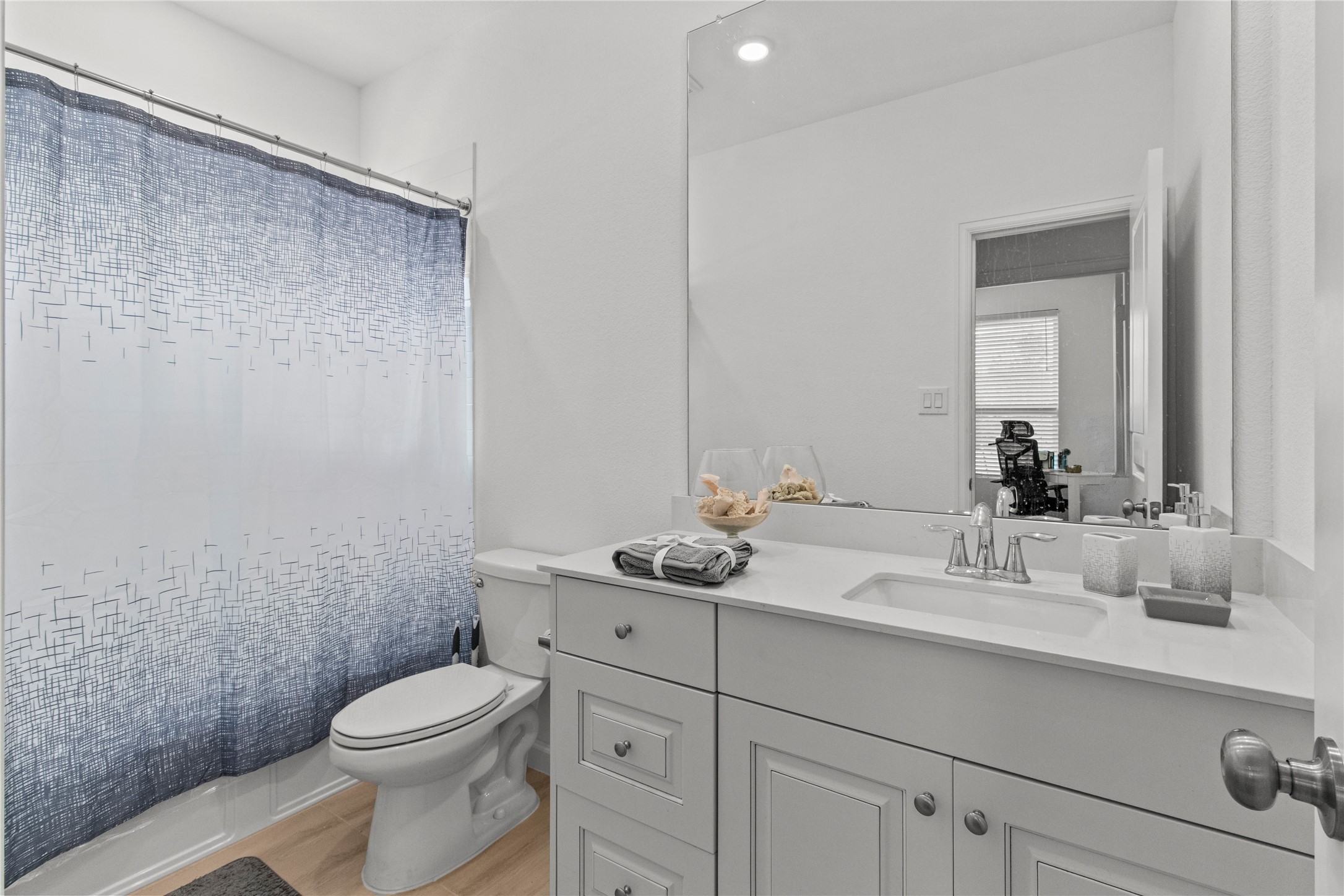 Bright and modern bathroom featuring a sleek vanity with ample storage, a large mirror, and a stylish shower curtain accentuating the space.