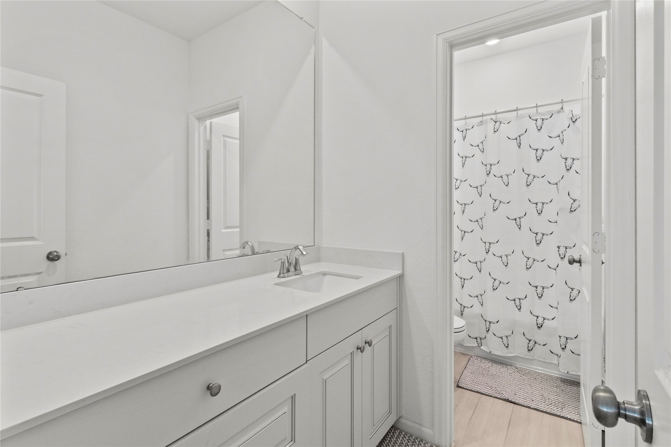 Bright, modern bathroom featuring a sleek vanity with ample counter space and a stylish shower curtain accent.
