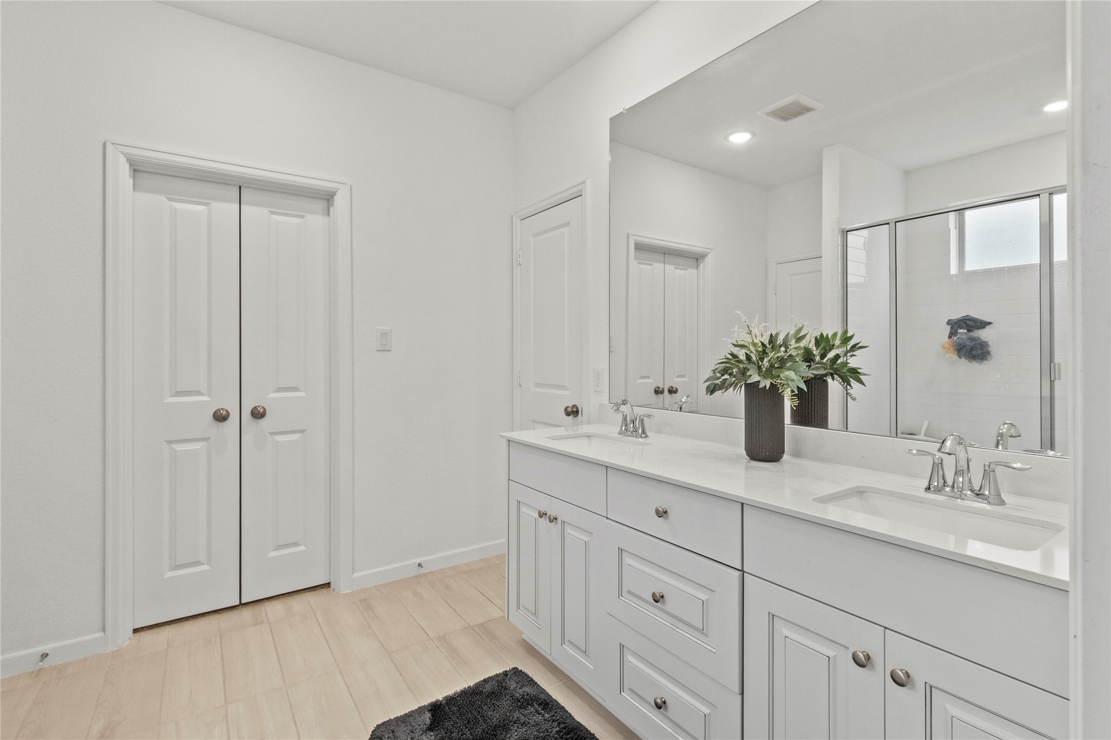 Bright and spacious bathroom featuring a double vanity with sleek countertops, ample storage, and a modern shower area for a luxurious feel.