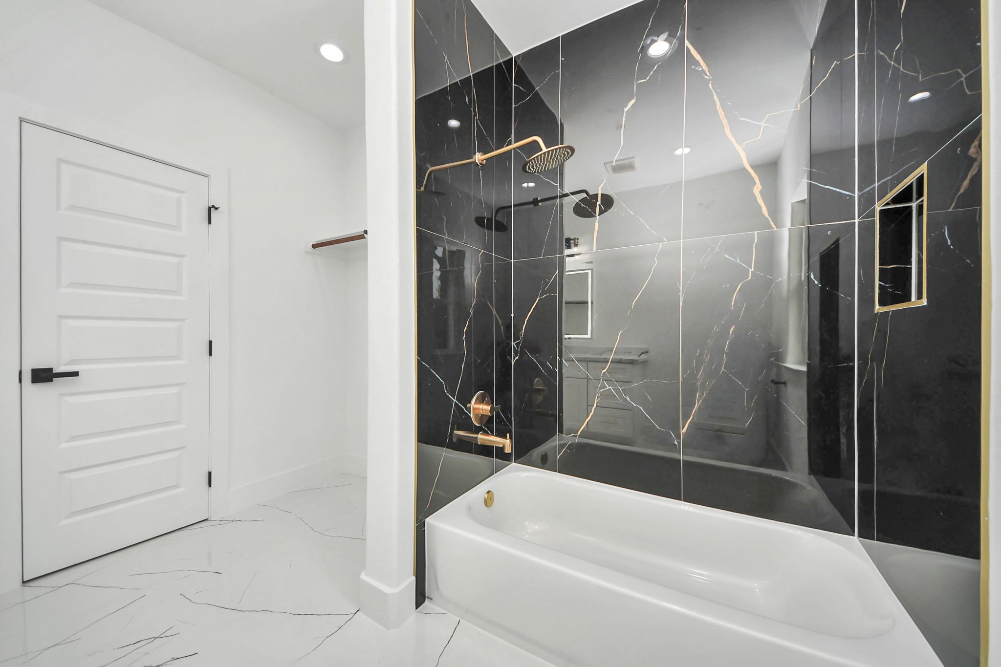 Luxurious bathroom featuring sleek black marble tiles with gold veining, a modern rainfall showerhead, and a pristine white bathtub, set against elegant white walls and flooring.